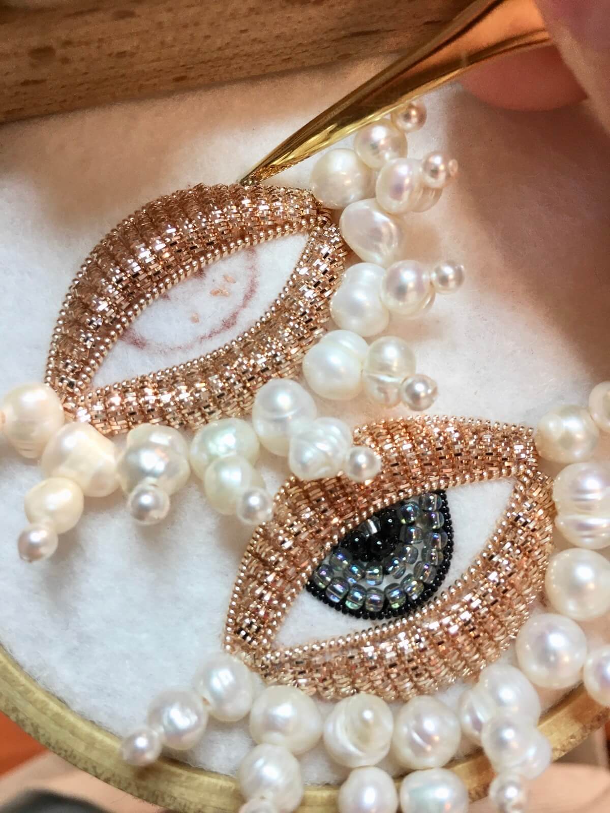 Process work of Carly beading her earrings on an embroidery loom