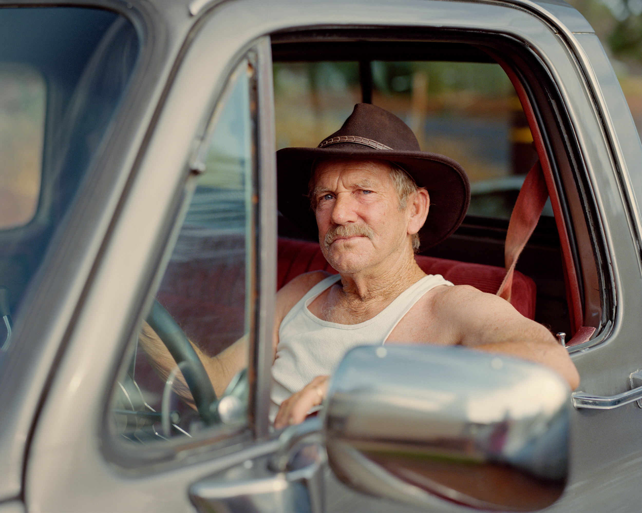 Jim McCurdy, in the car he is fixing in front of his new home.