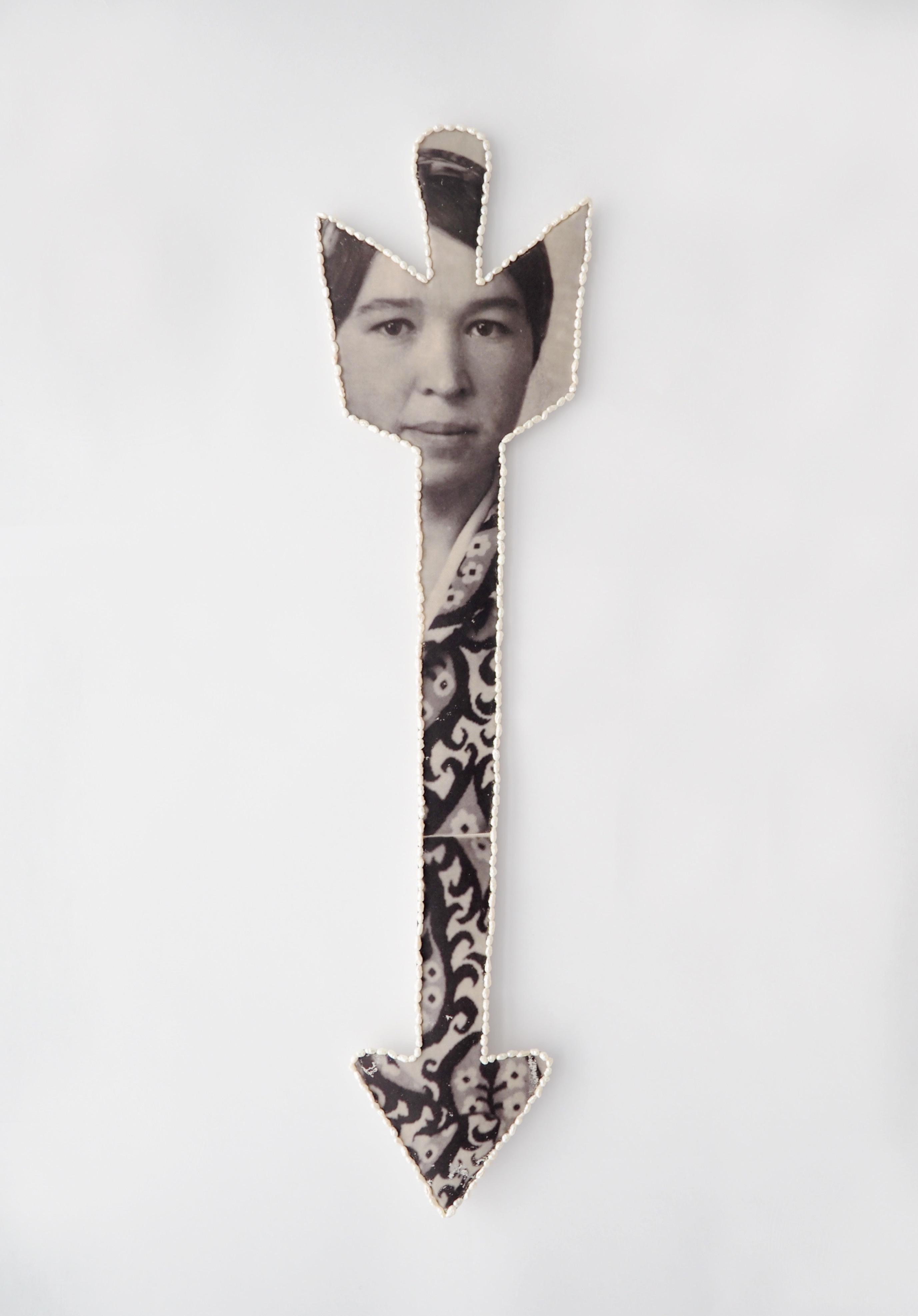 Arrow from archives, 2025 Archival family photo hand printed on textile, freshwater pearls, stainless steel wire, pressed cupboard, wool. 51 x 13 cm