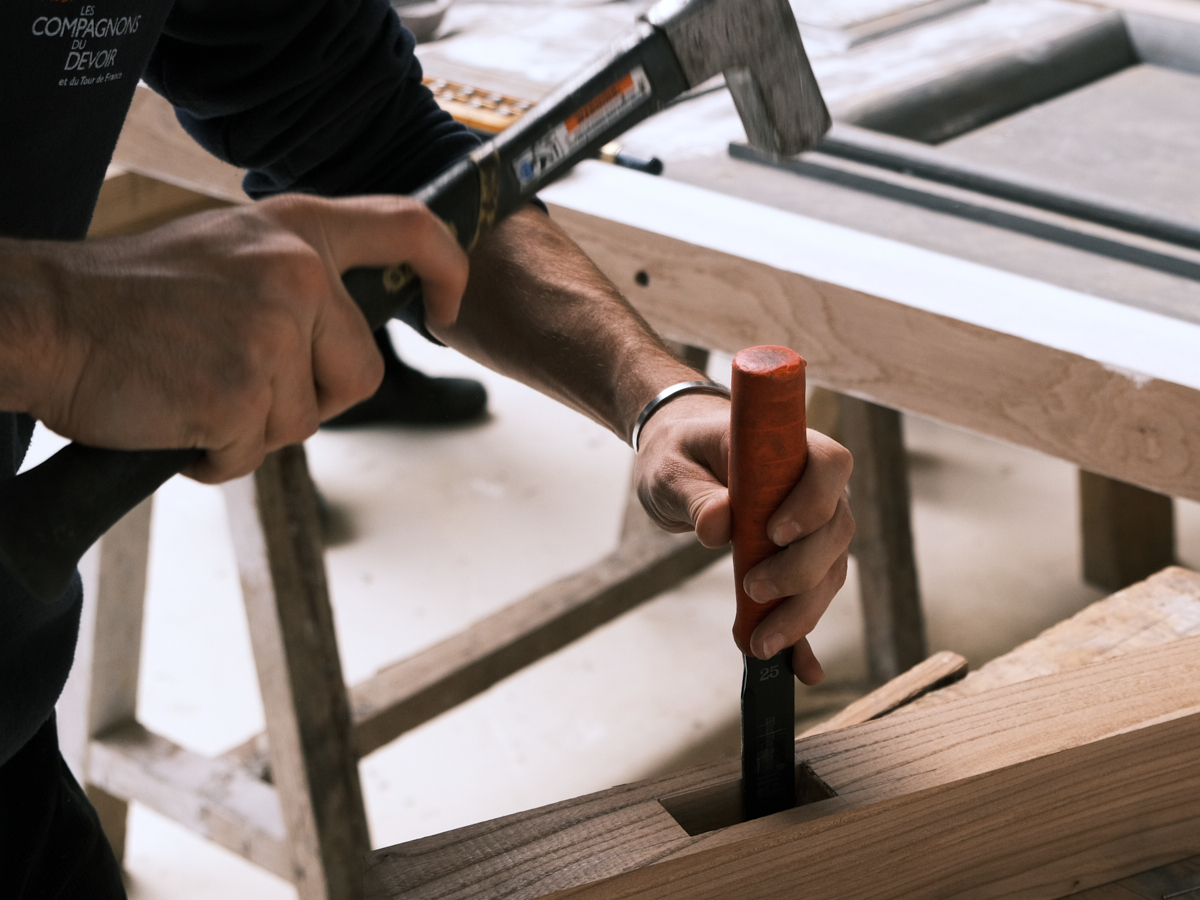 La mortaise est équarrie manuellement, la tronçonneuse ne permettant pas les détails d'angle droit. 