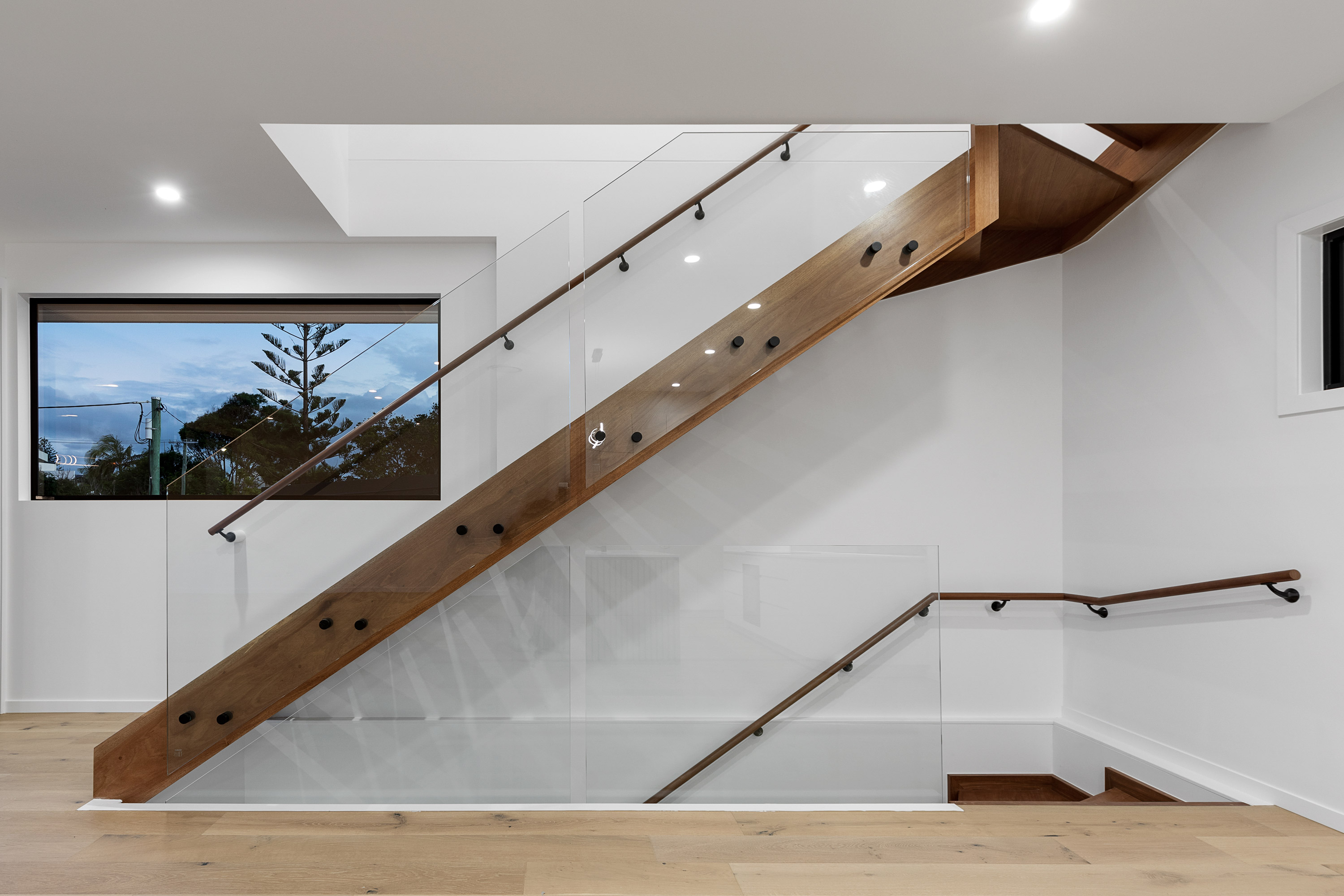 A contemporary staircase with sleek wood and glass railings, blending modern design with elegance.
