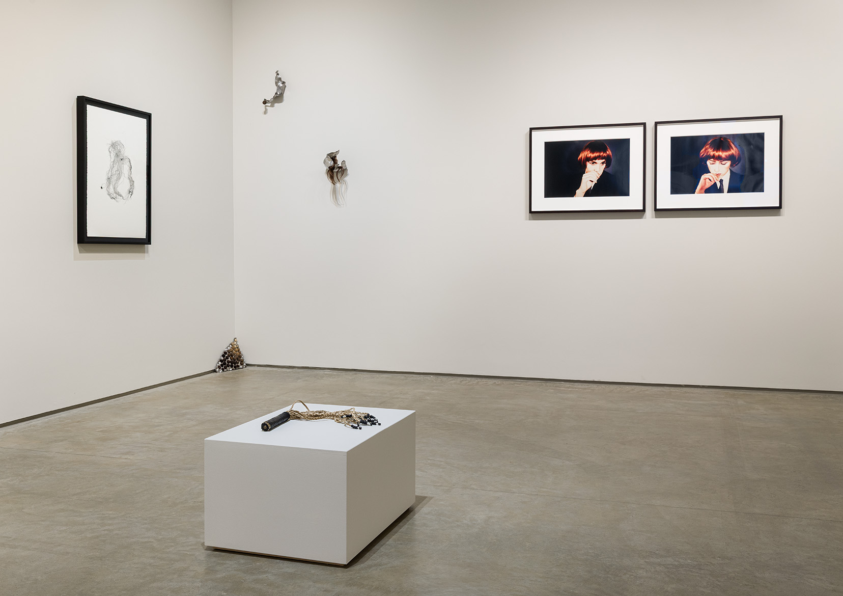 (Front) Calli Roche, All Inclusive, 2022. Leather, aluminum foil, synthetic braiding hair, plastic beads, dimensions variable. (Back, from left to right) Rebecca Bair, PRESSED, 2019. Monotype print, 30 x 22 inches.  Magdalena Dukiewicz, Object #4, 2022. Artist’s hair, steel, 10 x 13 x 2 inches.  Magdalena Dukiewicz, Object #2 , 2022. Artist’s hair, steel, 13 x 7 x 5 inches.  Magdalena Dukiewicz, Object #1, 2022.  Artist’s hair, steel, 11 x 8 x 8 inches. Richard Prince and Cindy Sherman, Double Self Portrait, 1980. Ektacolor photographs, 20 x 24 inches each. Photo by Etienne Frossard.