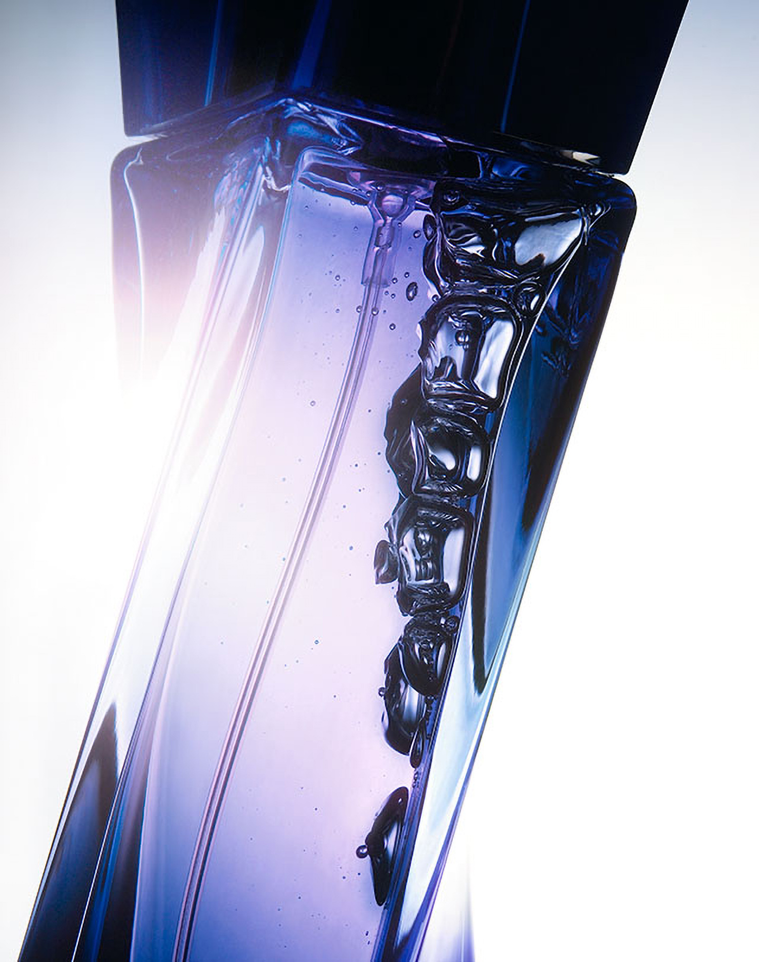 KMA photographer Daniel Schweizer photographs a close up photo of a purple tinted bottle of perfume with bubbles inside