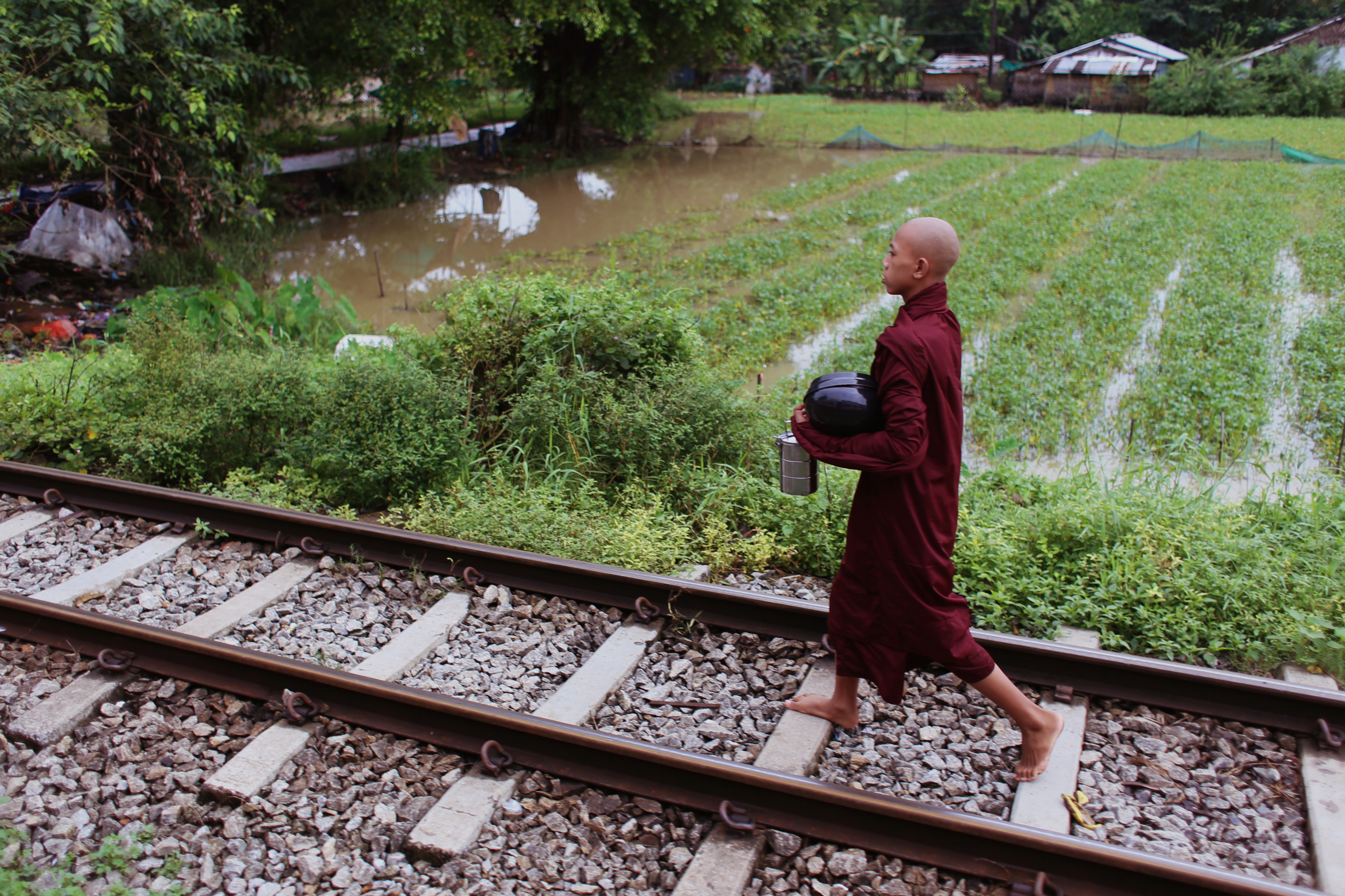 A monk walks along the tracks near some paddies, carrying his lunch. Agriculture is the main industry in Myanmar; the country was once Asia’s largest exporter of rice and even today rice remains the country’s biggest agricultural commodity. By the time the railway reaches its furthest outskirts, the crumbling shanties and dusty roads have given way to lush farmland.