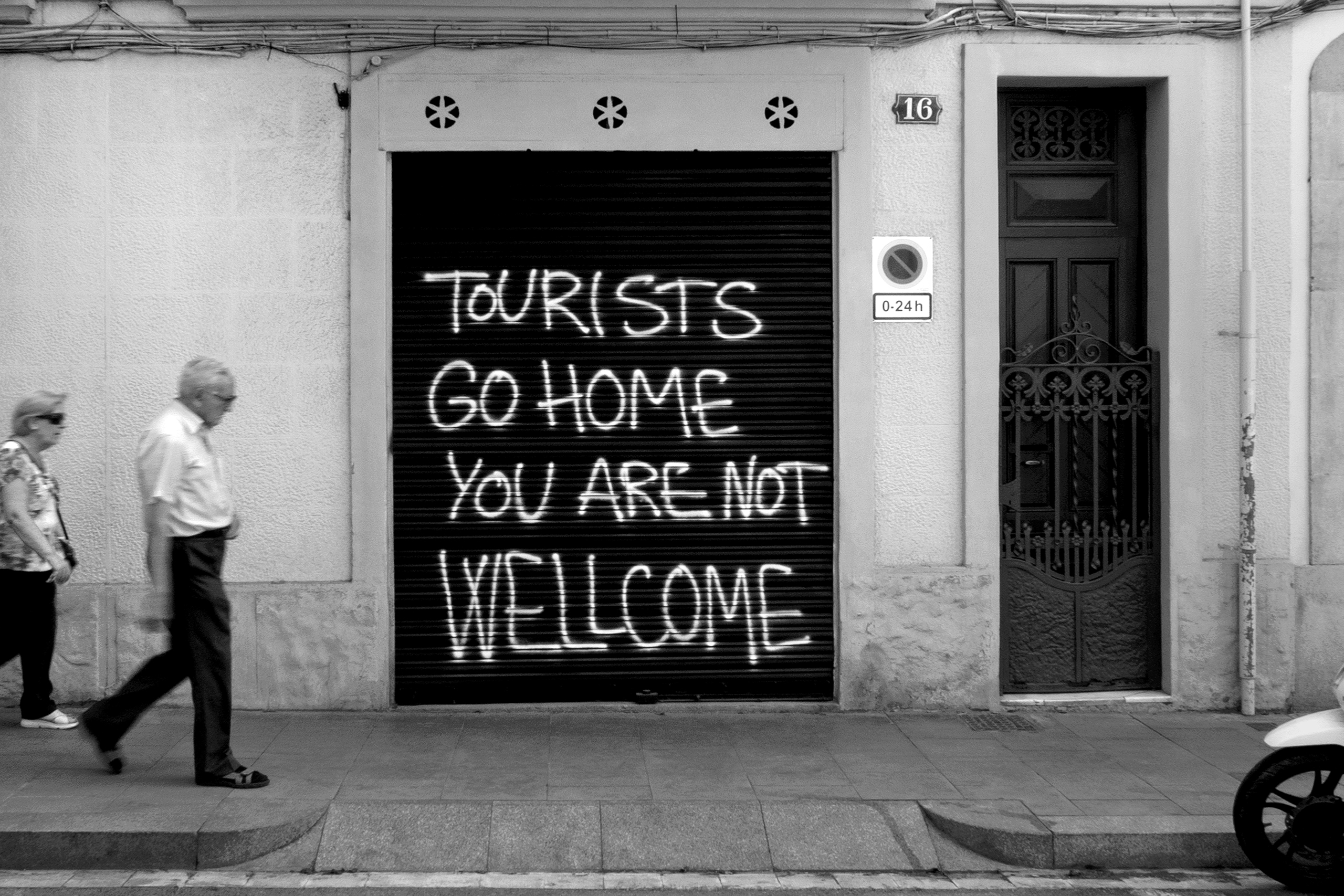 Senior couple and anti-tourist graffitiBarcelona, Spain, 2021photography, bw, single