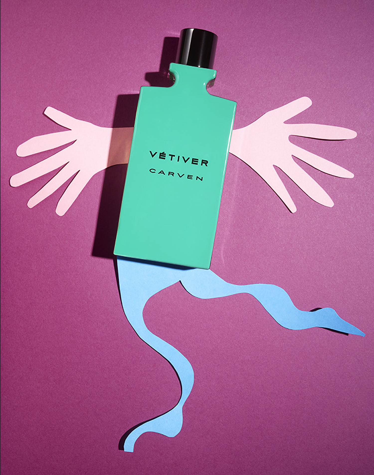 KMA photographer Daniel Schweizer shoots a photo of a green perfume bottle against a pink background with a cut out of a hand