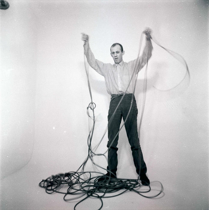 In this photo, artist Edward Krasiński holds with his two hands and up high a tangled cable, presumably looking for an end of the cable.