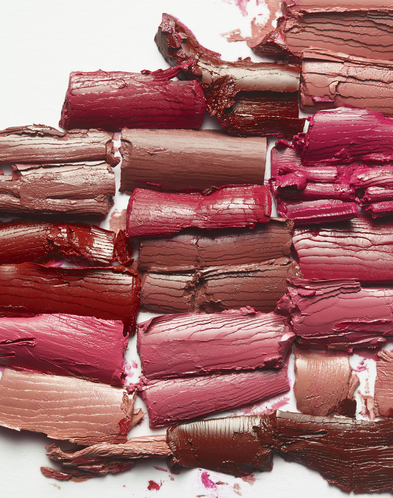 KMA photographer Daniel Schweizer shoots a photo of broken red and pink lipsticks smeared on a white surface 