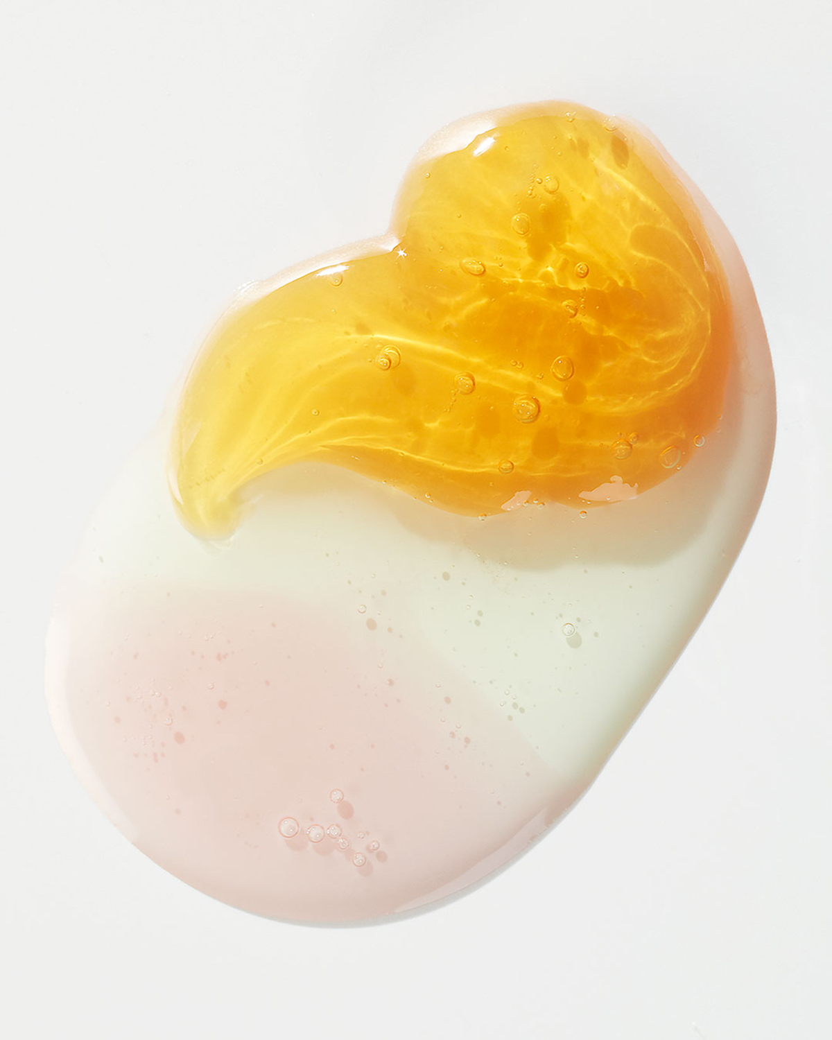 KMA photographer Vincent Gapaillard takes a texture photo of clear orange liquid with bubbles inside on a white surface