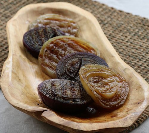 An artfully placed picture of grilled onion in a wood bowl