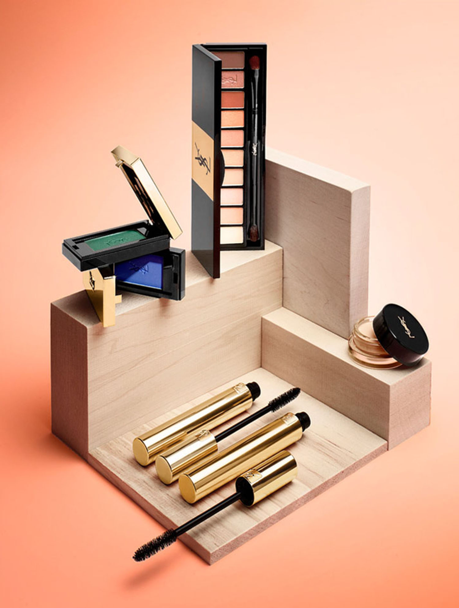 KMA stylist Sara Wacksman designs set for photo of many YSL beauty products arranged on a wooden box with pink background