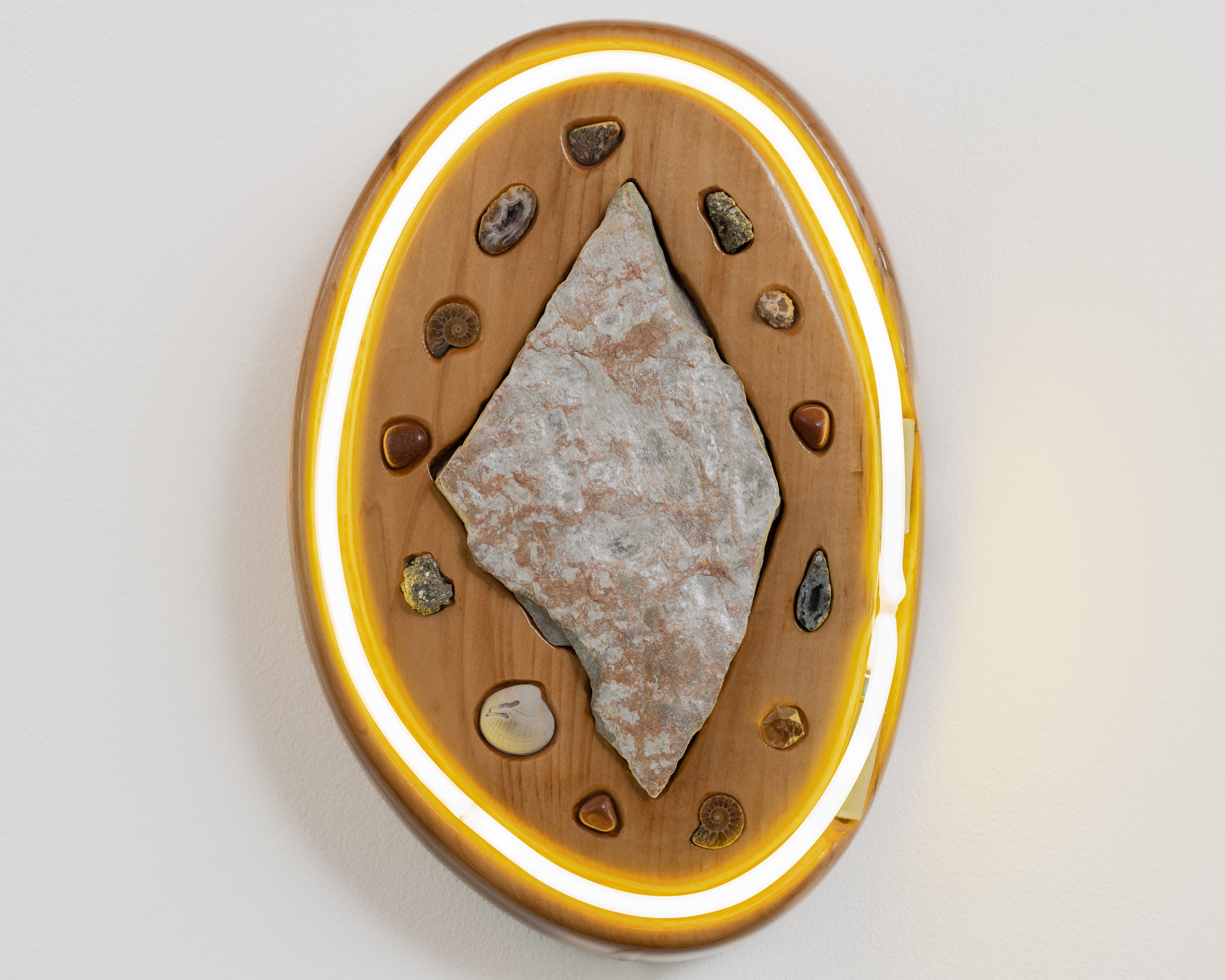 Beacon X (Timepiece), 2024, Basswood, white glass, phosphor, mercury, argon, muscovite schist, brown ammonites, geodes, goldstones, pyrite, quartz, seashells, leopard skin jasper, epoxy clay, transformer, polyurethane, 17 x 11.5 x 5 in, $7,500