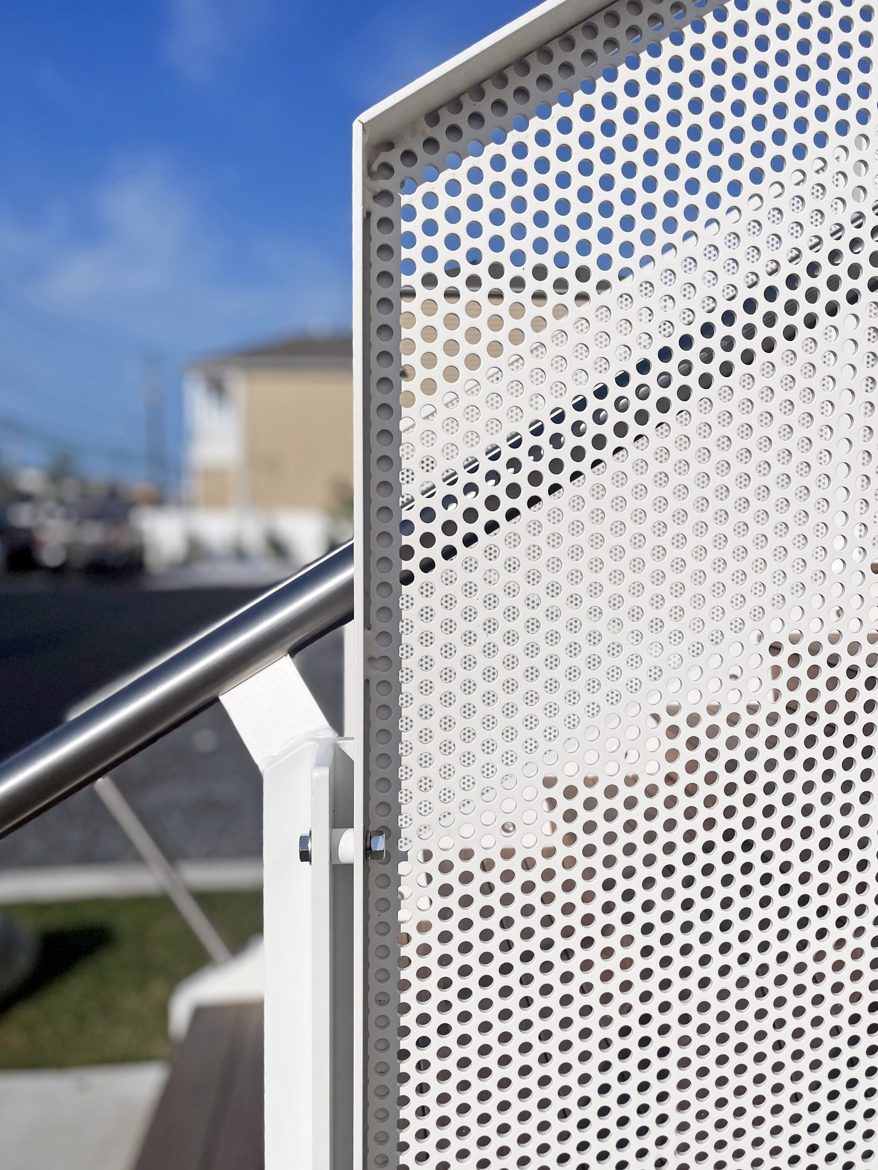 Detail photo of the Brigantine Marina Paddle Club's main entry stair, highlighting the contemporary white perforated metal railing and stainless steel handrail.