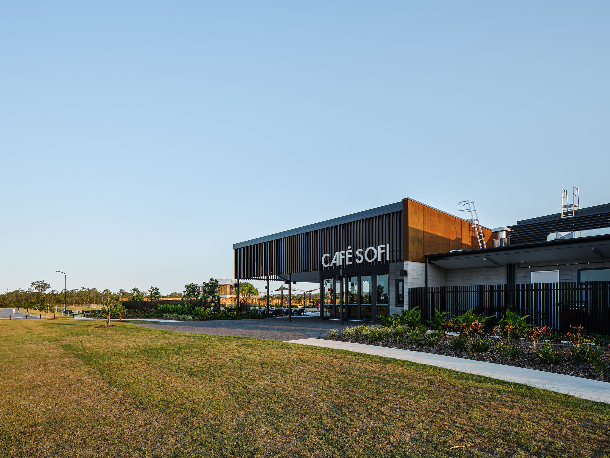 Exterior view of Café Sofi located within The Surrounds Leisure Centre, with a well-maintained lawn and pedestrian path in the foreground.