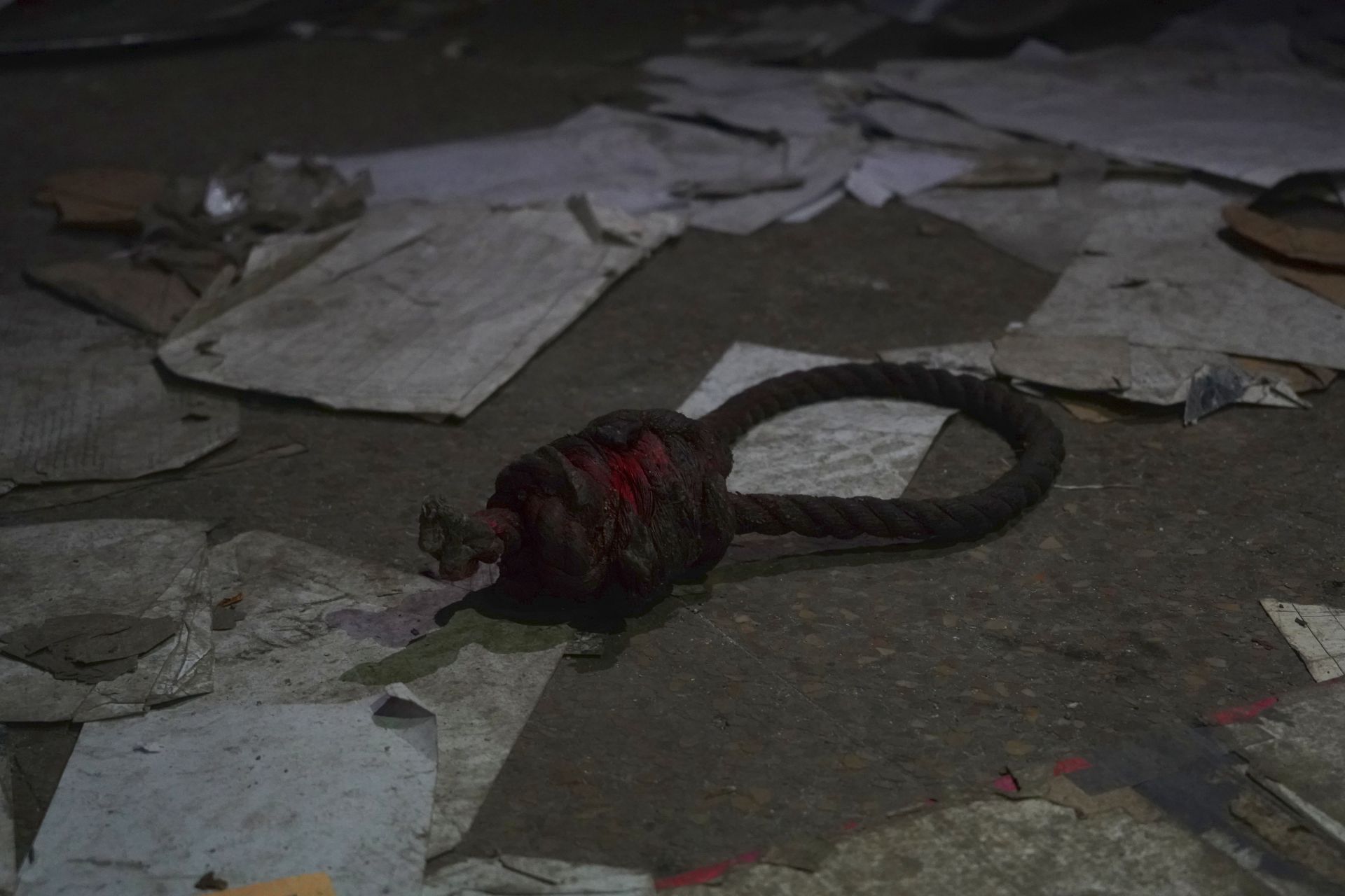 A severed noose lays on the floor of a prison cell.
