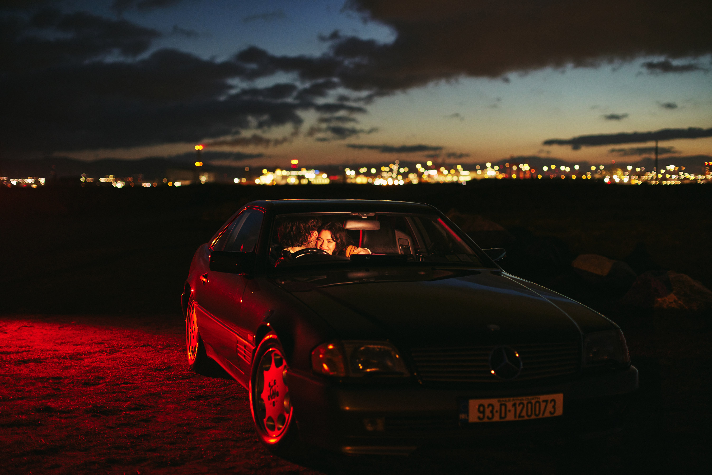 A story of young love in the suburbs told through photography, featuring stylish models in vintage clothing, photographed at sunset in Dublin, Ireland by fashion and lifestyle photographer Alex Sheridan. Suburban Love photo series. Featuring a vintage 1993 Mercedes Benz SL class and cinematic lighting and red light. Euphoria inspired photoshoot.
