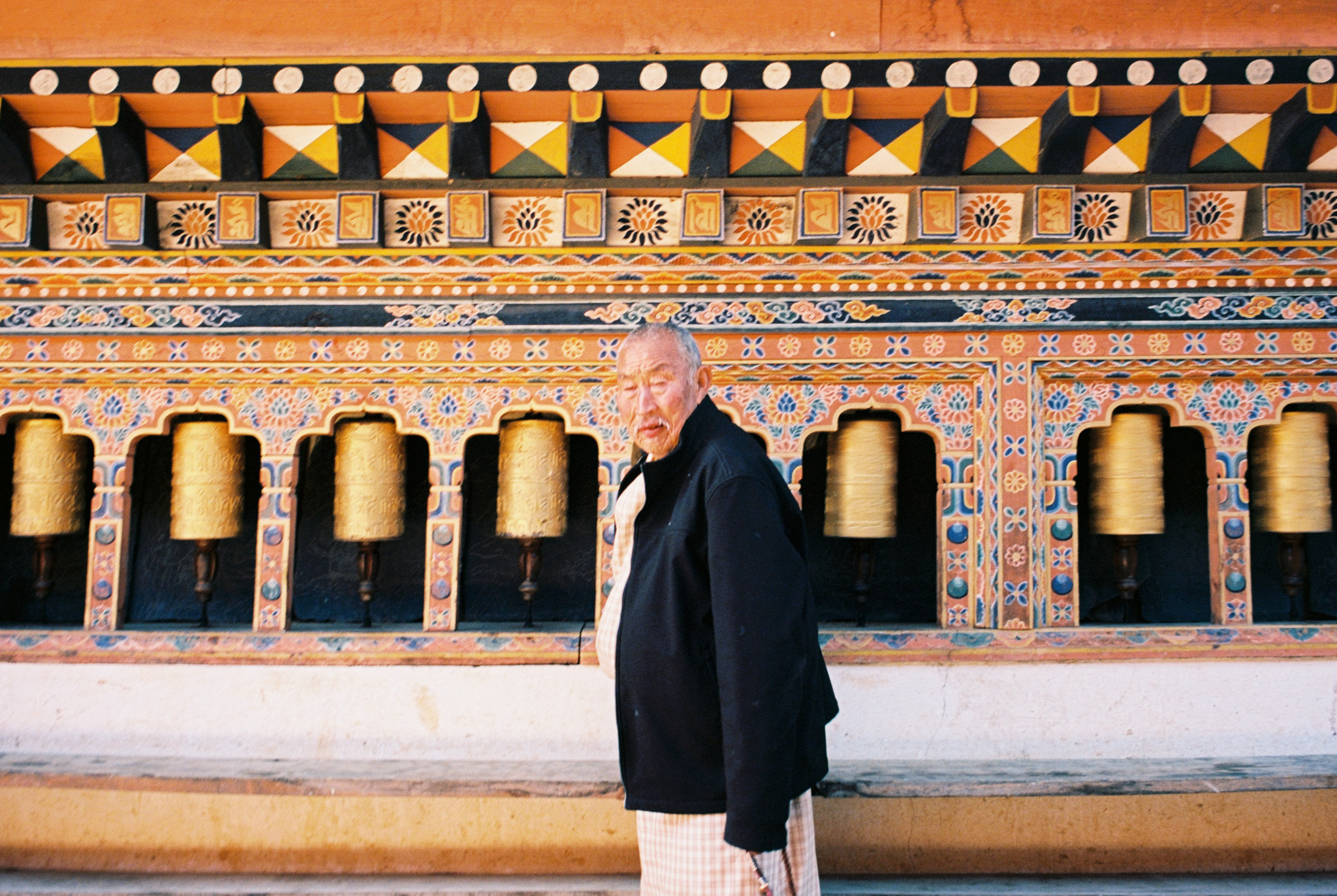 An older monk spins prayer bells