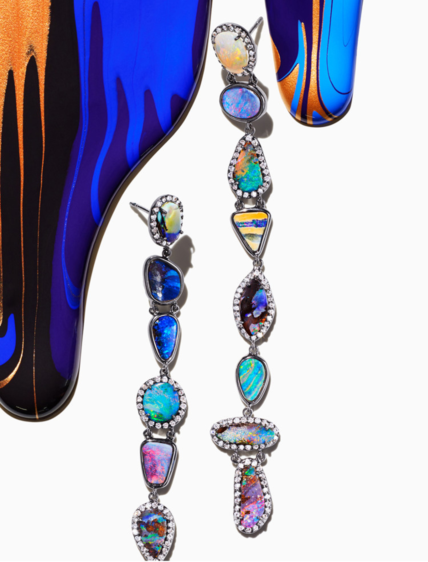 KMA stylist Sara Wacksman designs set for abstract photo of blue paint dripping on white background with colorful earrings  