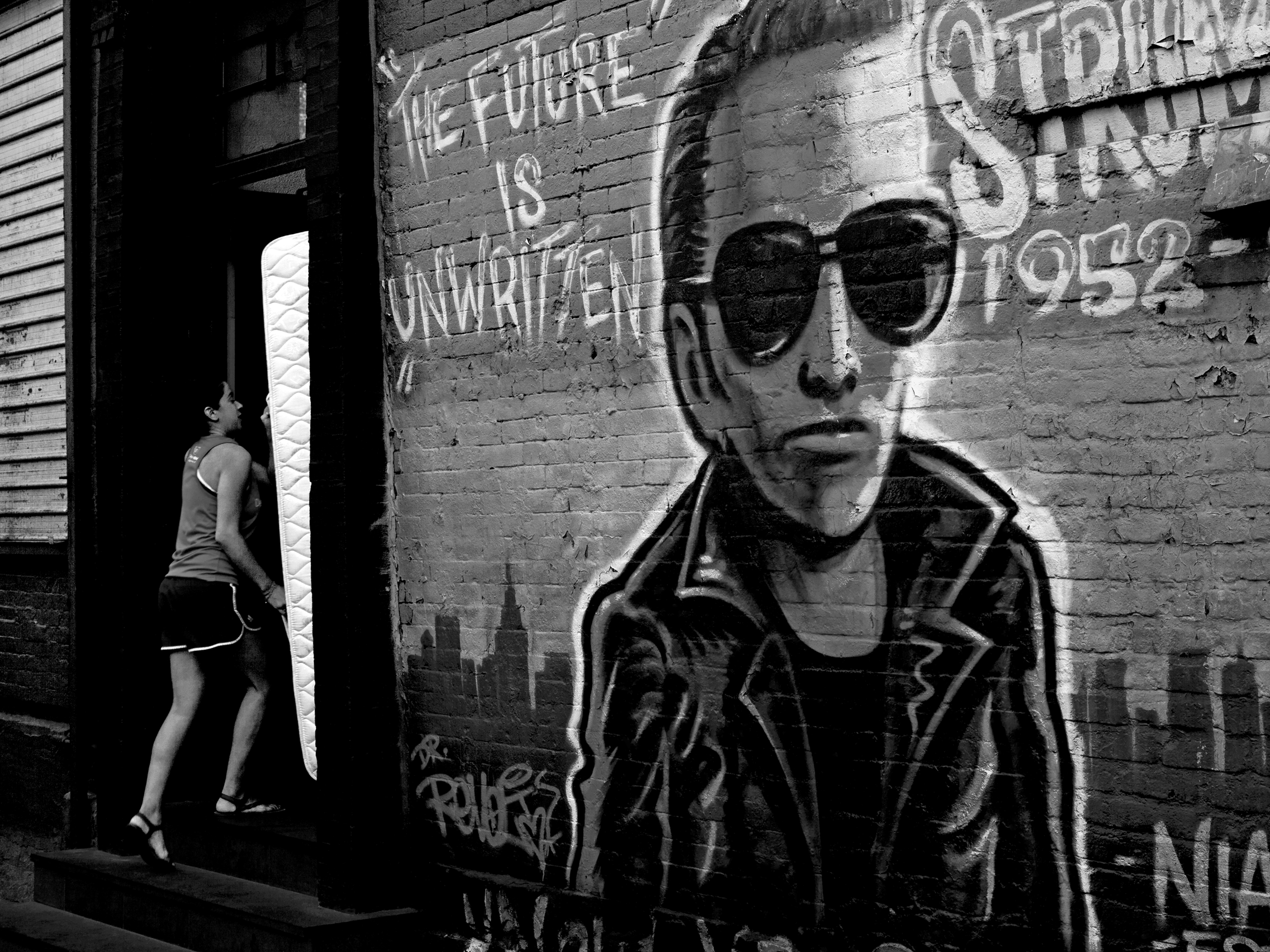 Girl carrying a mattress next to punk graffiti New York, United States, 2012photography, bw, single