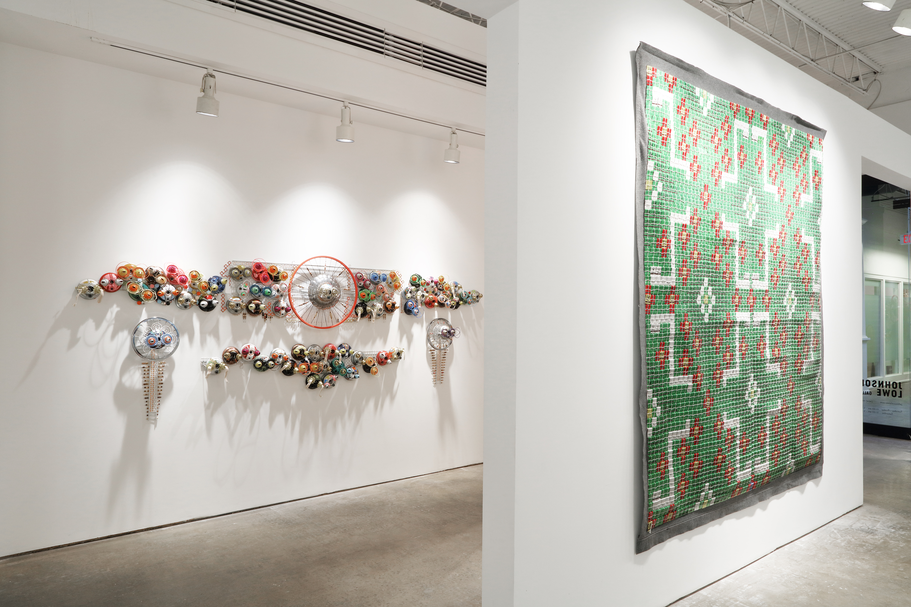 Art exhibition in a white wall gallery space. Two works can be seen, each on their own wall, one behind and one nearer.