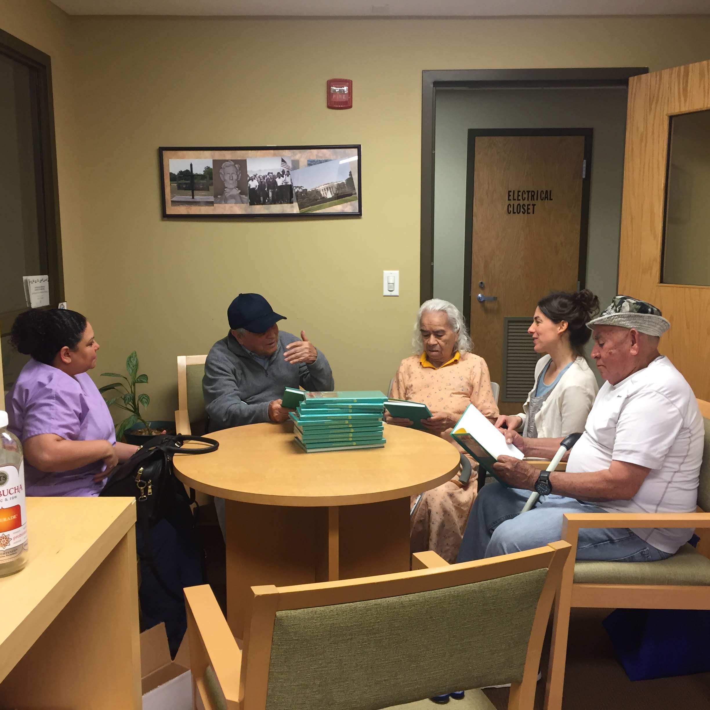  3 senior centers, a home health aid, and a woman talking at a round table containing a stack of books.