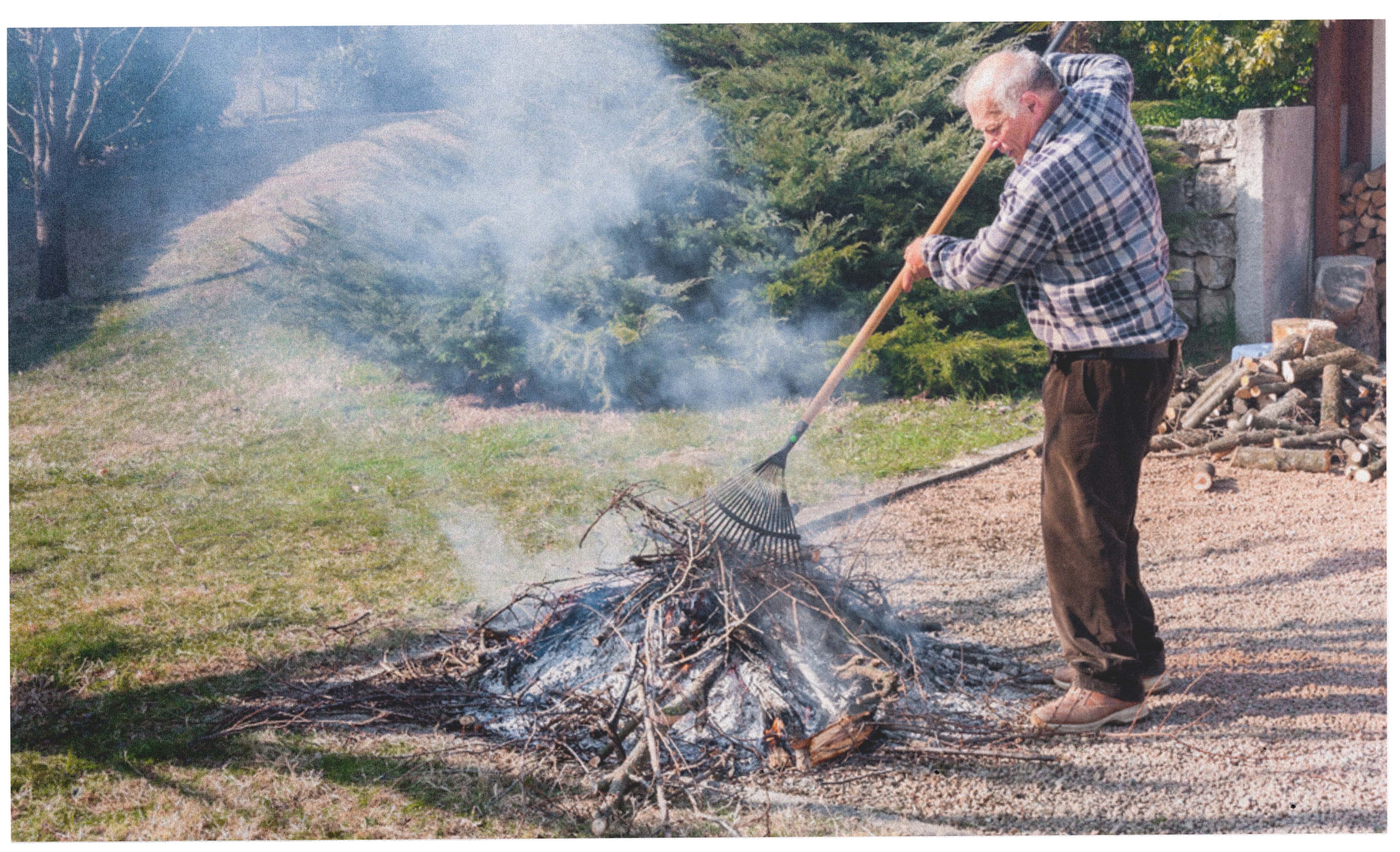 a man sweeping up a burning pile of sticks