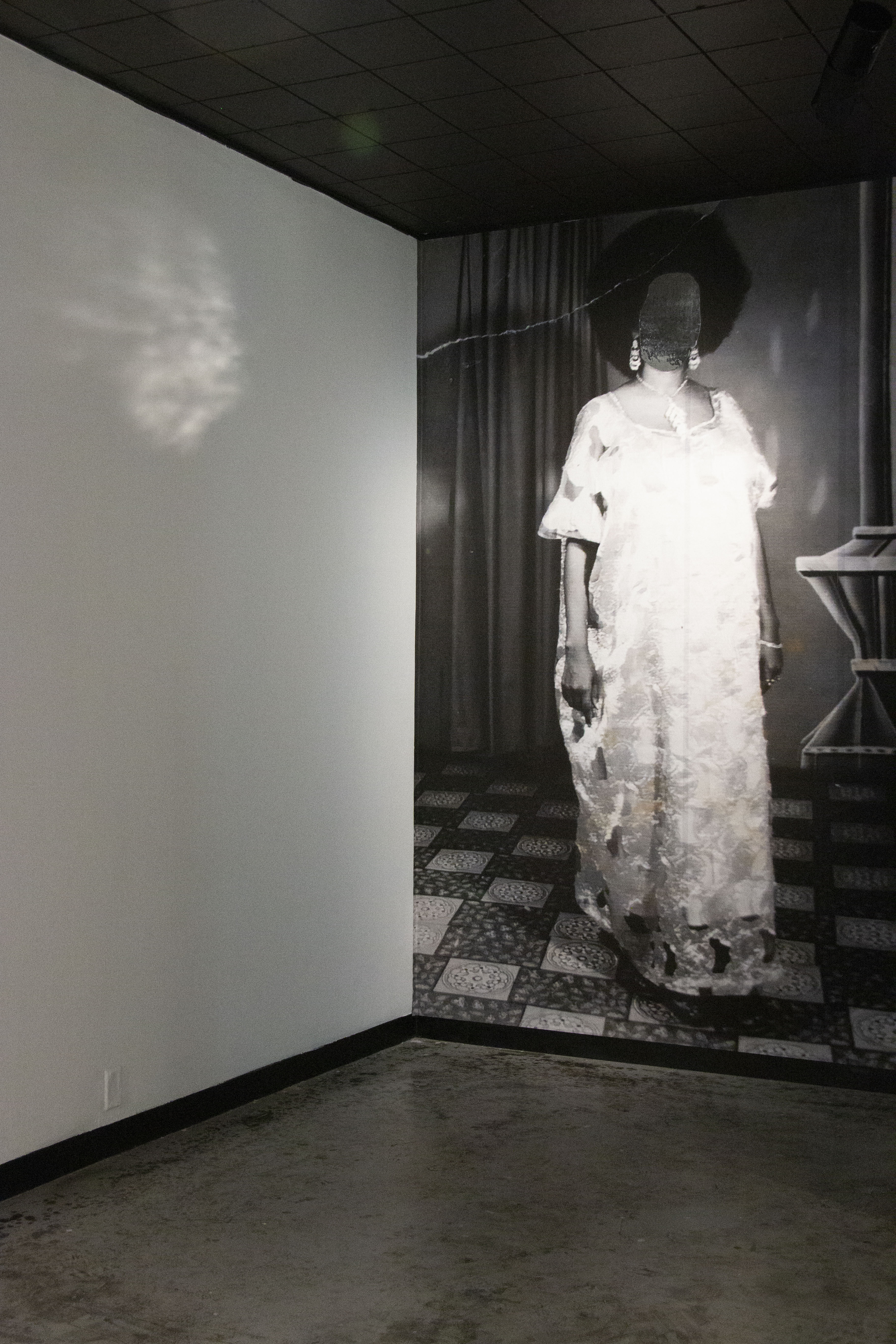 Studio portraits of mother and daughter (February 1974 / የካቲት ፲፱፻፷፮, Yekatit 1966, E.C. and June 1982 / ሰኔ ፲፱፻፸፬, Sene 1974, E.C.), eve of revolution / eve of  separation, 2019  installation with printed vinyl mounted to wall, original photograph scaled to height of wall, reflective vinyl, drywall, projection, time and distance. Dimensions variable