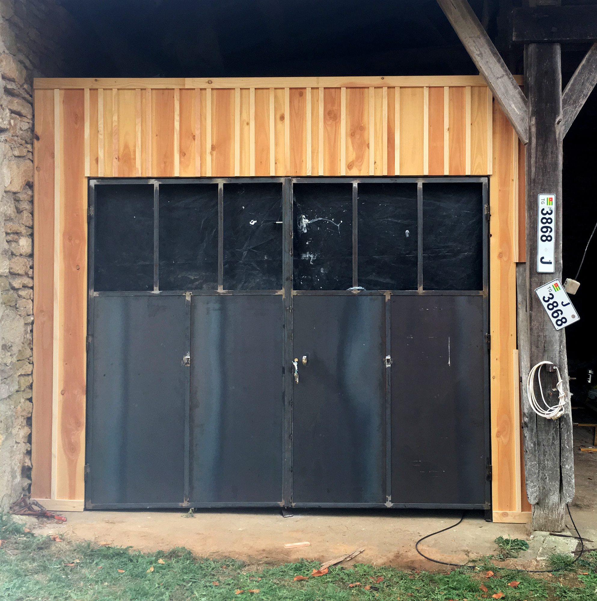 Fabrication d'une porte de garage en acier entourée d'une façade en pin