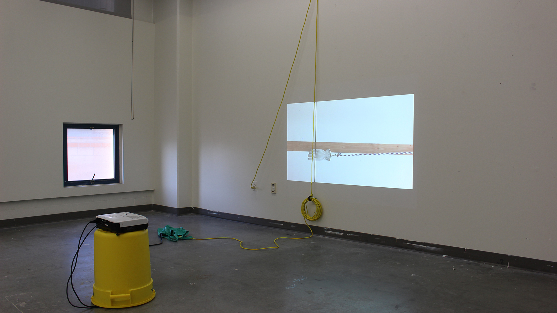 with friends, 2015. Yellow bucket, video projection, extension cords, hardware, acrylic latex paint and projector. Variable dimensions
