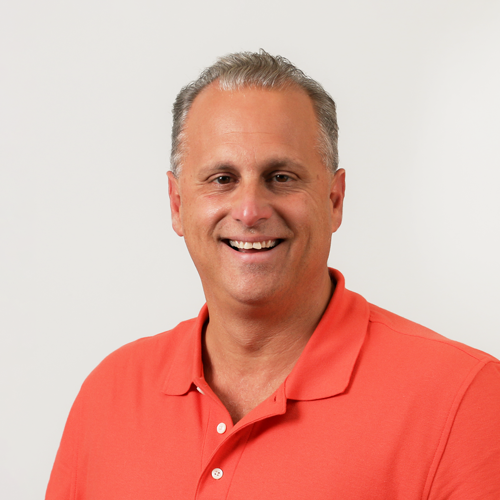 Headshot of Greg Cardamone. He is wearing a salmon colored polo.