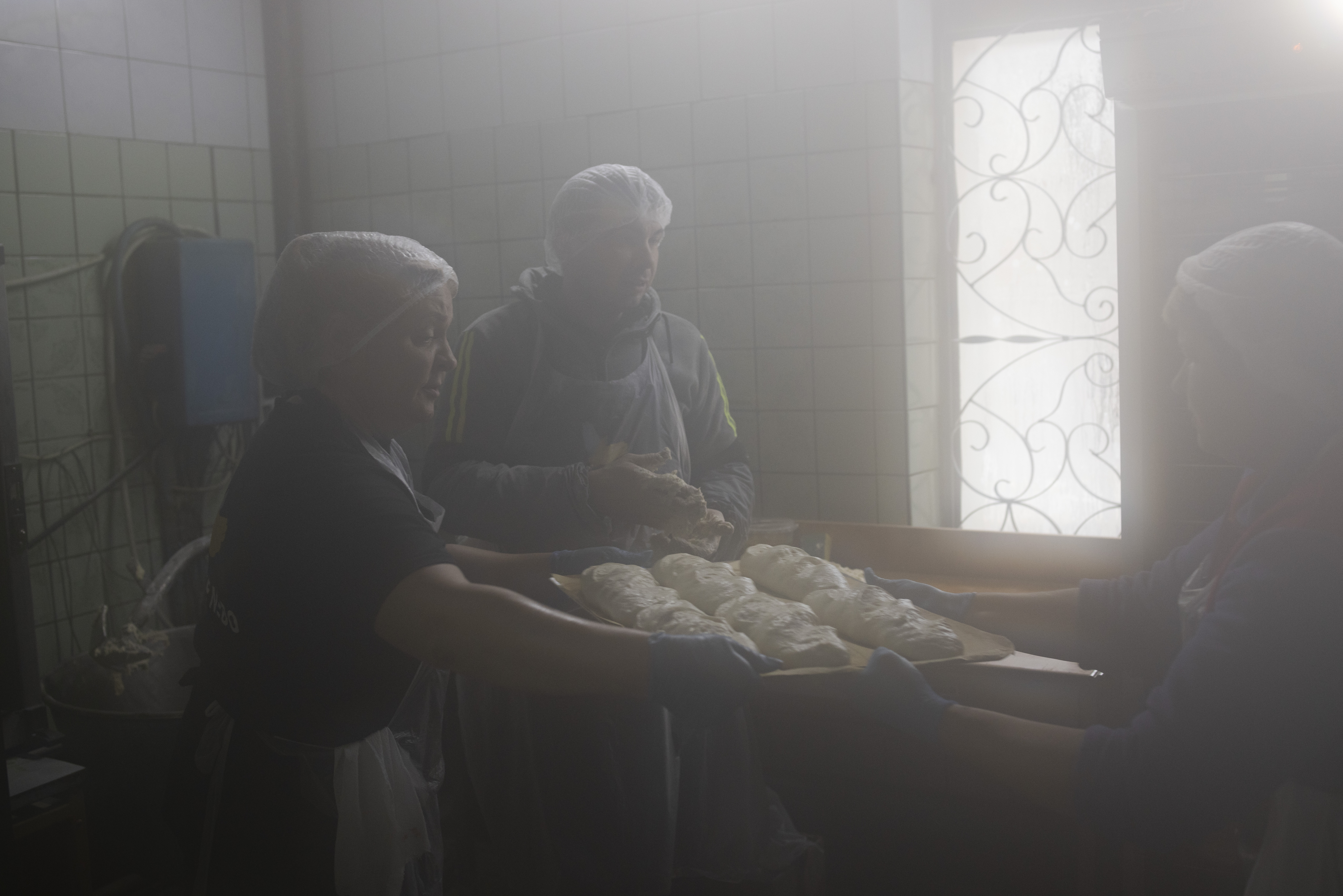 Olga, Vitali and Svetlana working for a charitable organization Peaceful Heaven of Kharkiv (Мирне Небо Харкова), bake some 500 breads a day to assist the people living in the war-torn city of Izium.