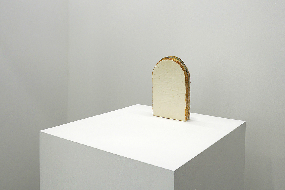 A sculpture in an arch form installed on a pedestal.