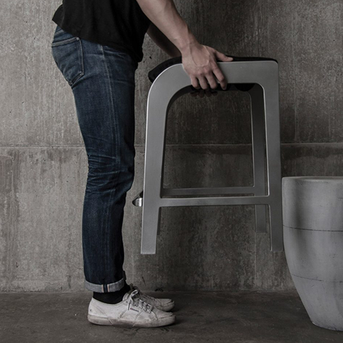 Person lifting a chair designed by a BA Product Design student for prison cell use