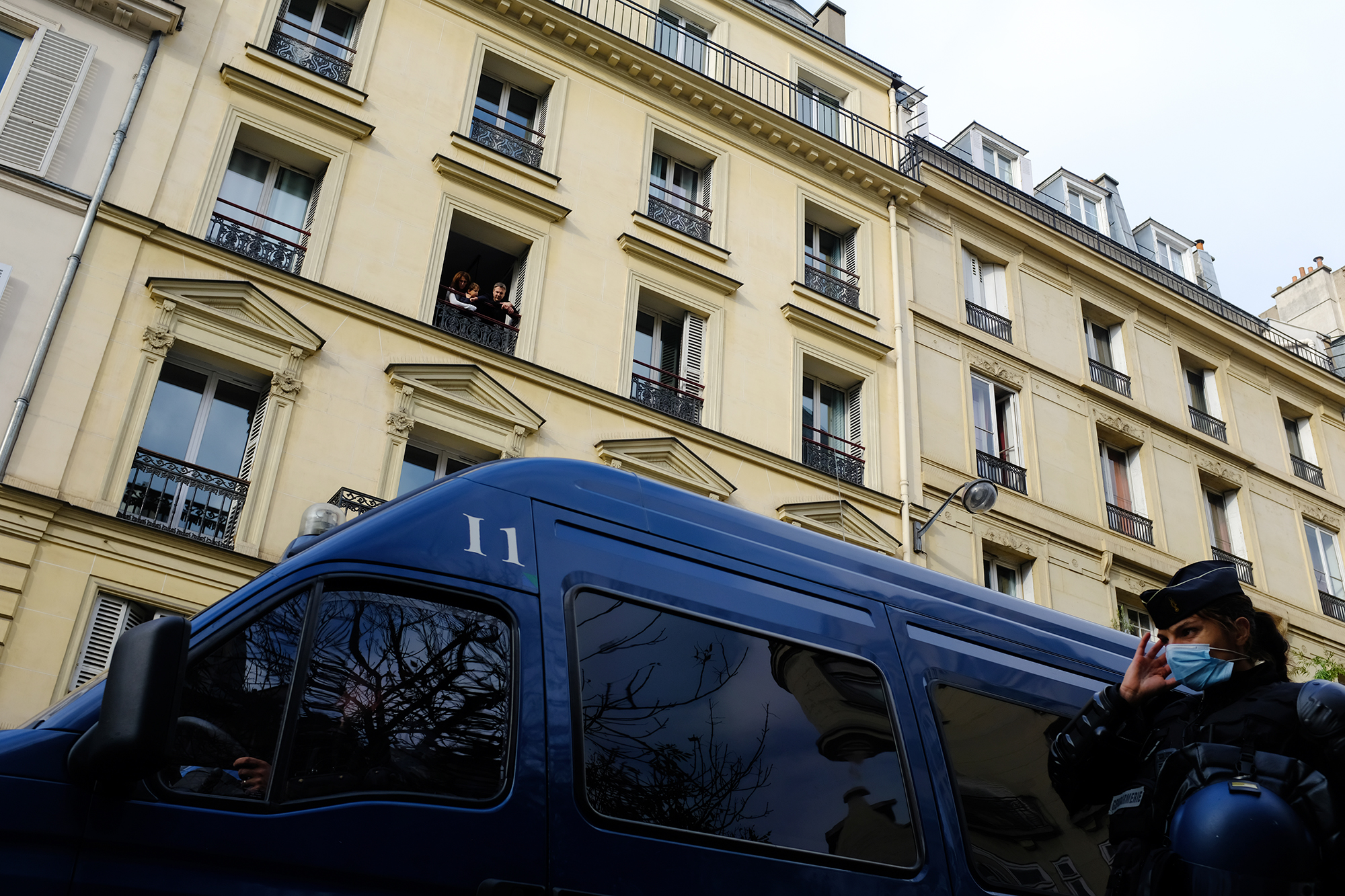 Philippe-Sarfati-reportage-photography-photographer-street-documentary-photojournalism-photojournalist-covid-19-pandemic-lockdown-paris-france-family-window-haussmann-rue-lafayette-police-van-crs-woman-uniform-blue