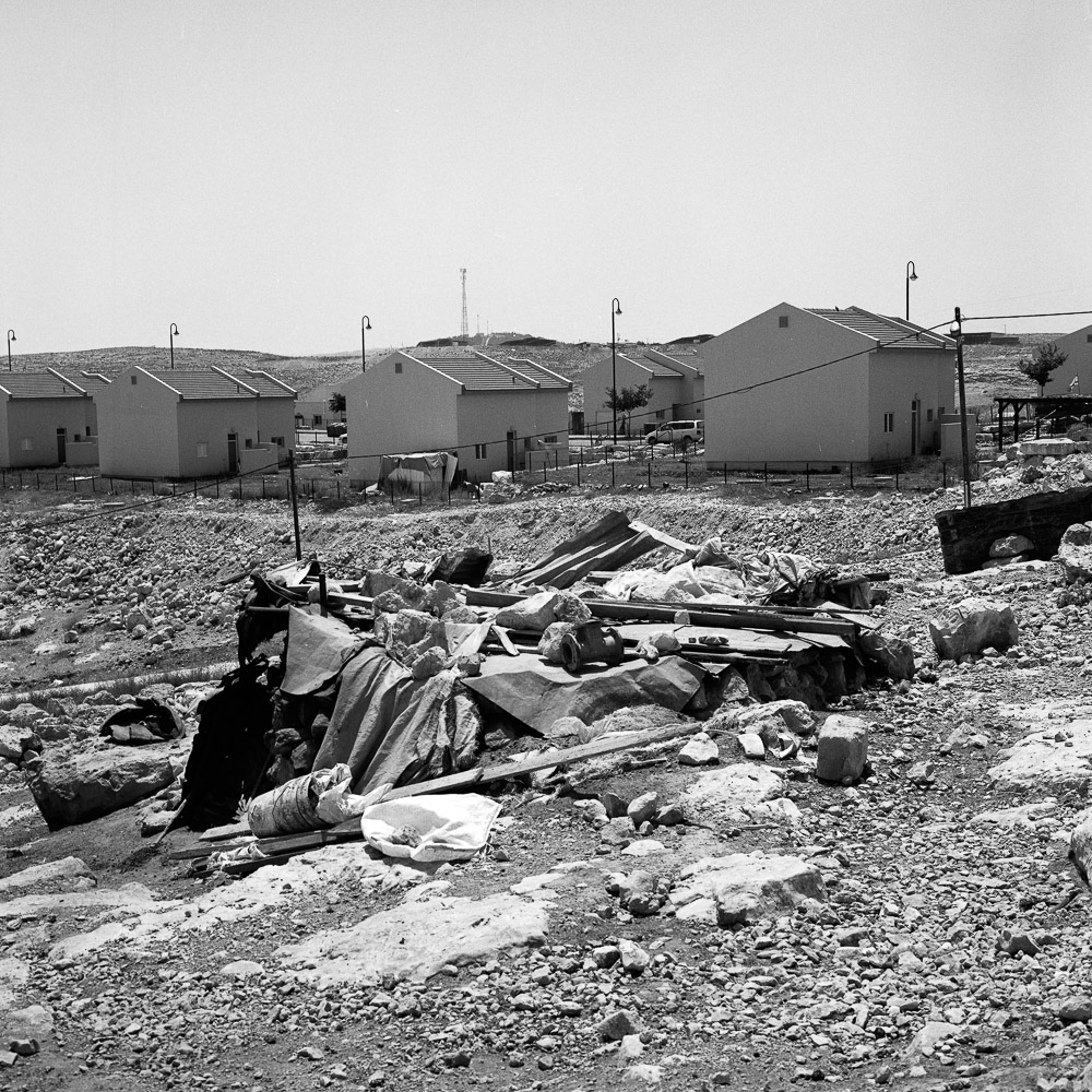 Um Al Khayr, july 2011. Derri&egrave;re le village des b&eacute;douins, la colonie &eacute;tire ses maisons, toutes identiques et pos&eacute;es les unes &agrave; c&ocirc;t&eacute; des autres, comme des bo&icirc;tes. Les colons emp&ecirc;chent les b&eacute;douins d'avoir acc&egrave;s &agrave; l'eau, et d&eacute;truisent toute construction trop proche du grillage qui les s&eacute;parent.