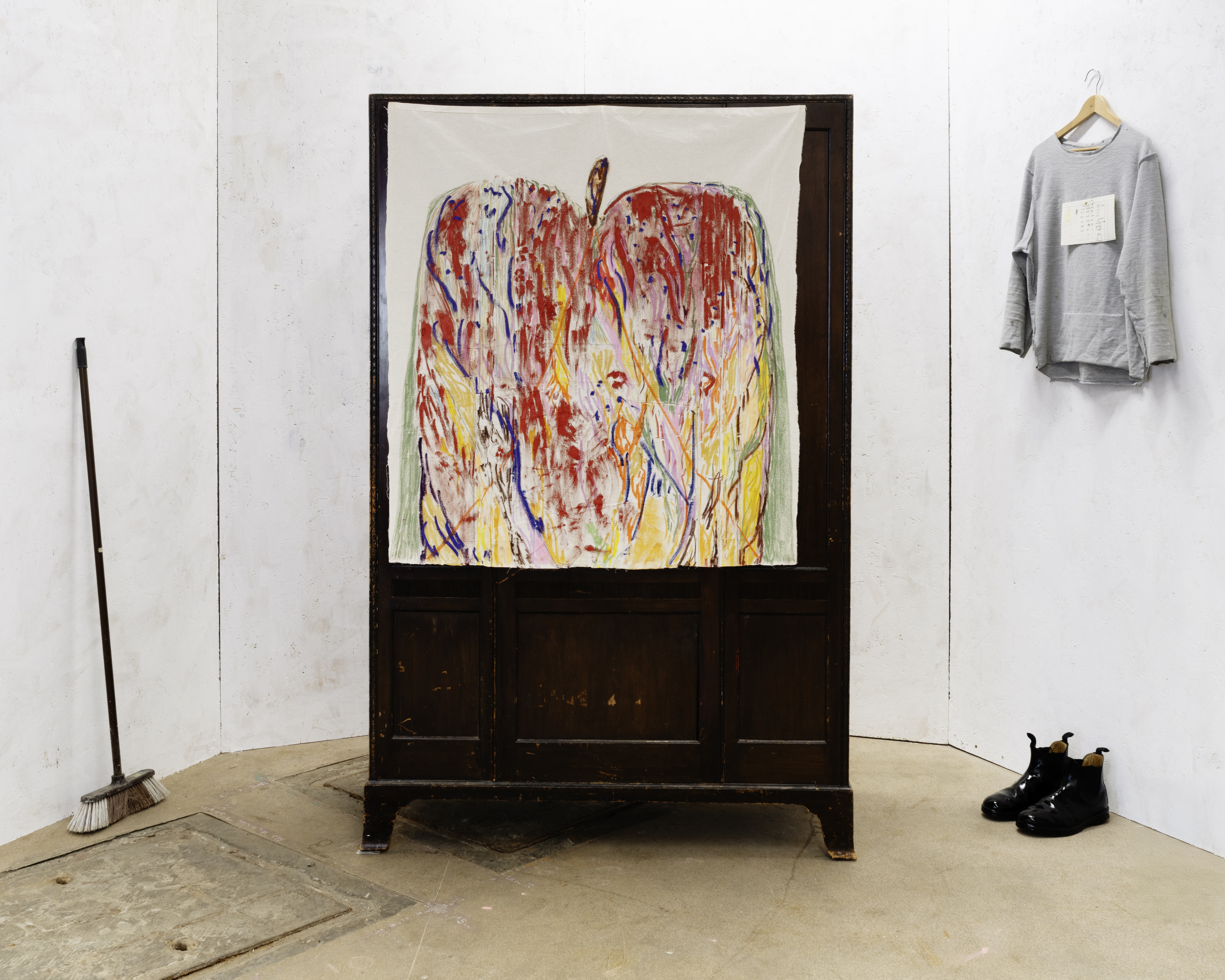 σκηνή / Stage, 244x333x170cm, comprised of: I) Untitled (Apple 14), 2025, oil, soft pastel, biro, & graphite on cotton, on imitation Edwardian wardrobe 187x119x51cm II) Studio broom III) Artist’s sweater W/ dimensions notes & safety pin IV) Artist’s boots W/ black iron gate paint