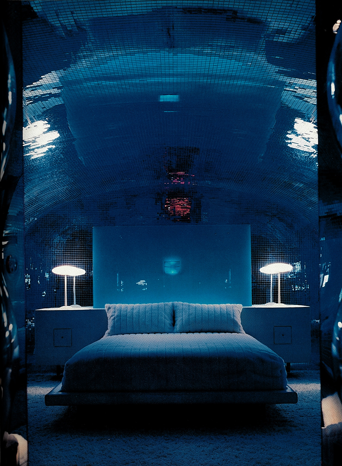 Blue futuristic bedroom, the walls are covered floor to ceiling in disco tiles.