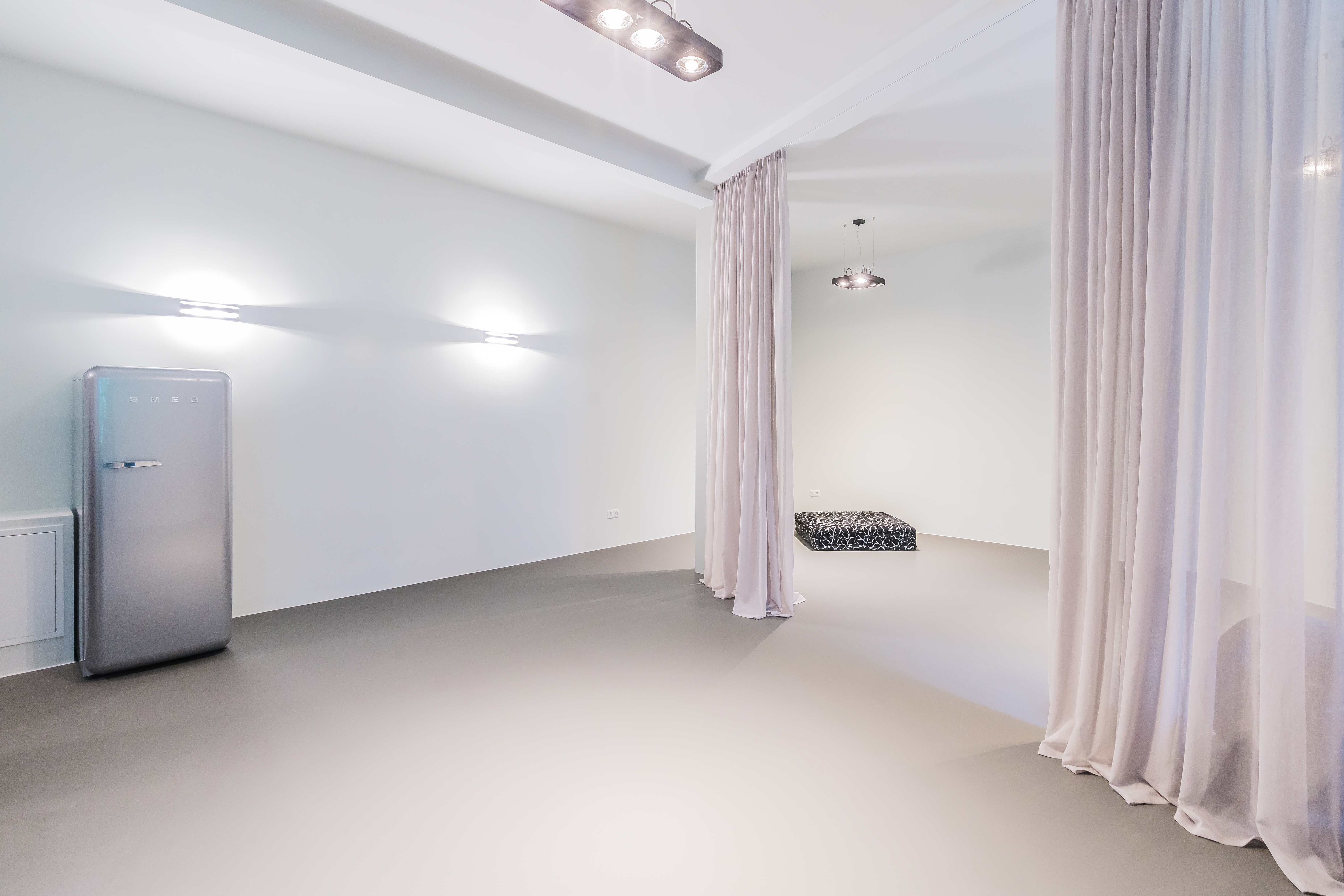 Der weite Raum lässt sich durch einen transluzenten Vorhang teilen. Im vorderen Bereich befindet sich eine maßgefertigte Teeküche und ein Bartisch.Foto: Boris Storz