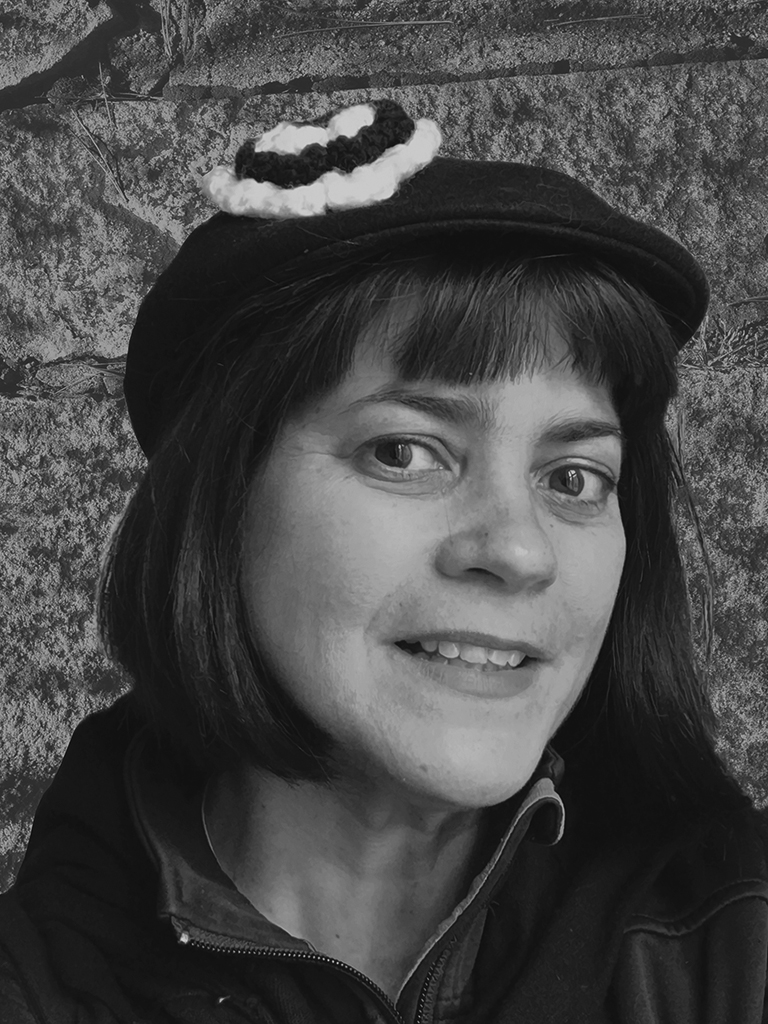 Woman with short hair wearing a hat and smiling