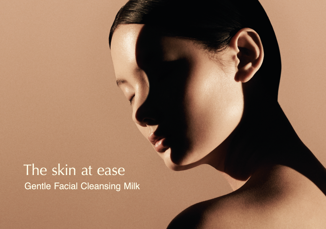 A person with well-maintained skin appears at ease; light falls across their face like a gentle caress. Overlaid copy reads: The skin at ease, Gentle Facial Cleansing Milk.