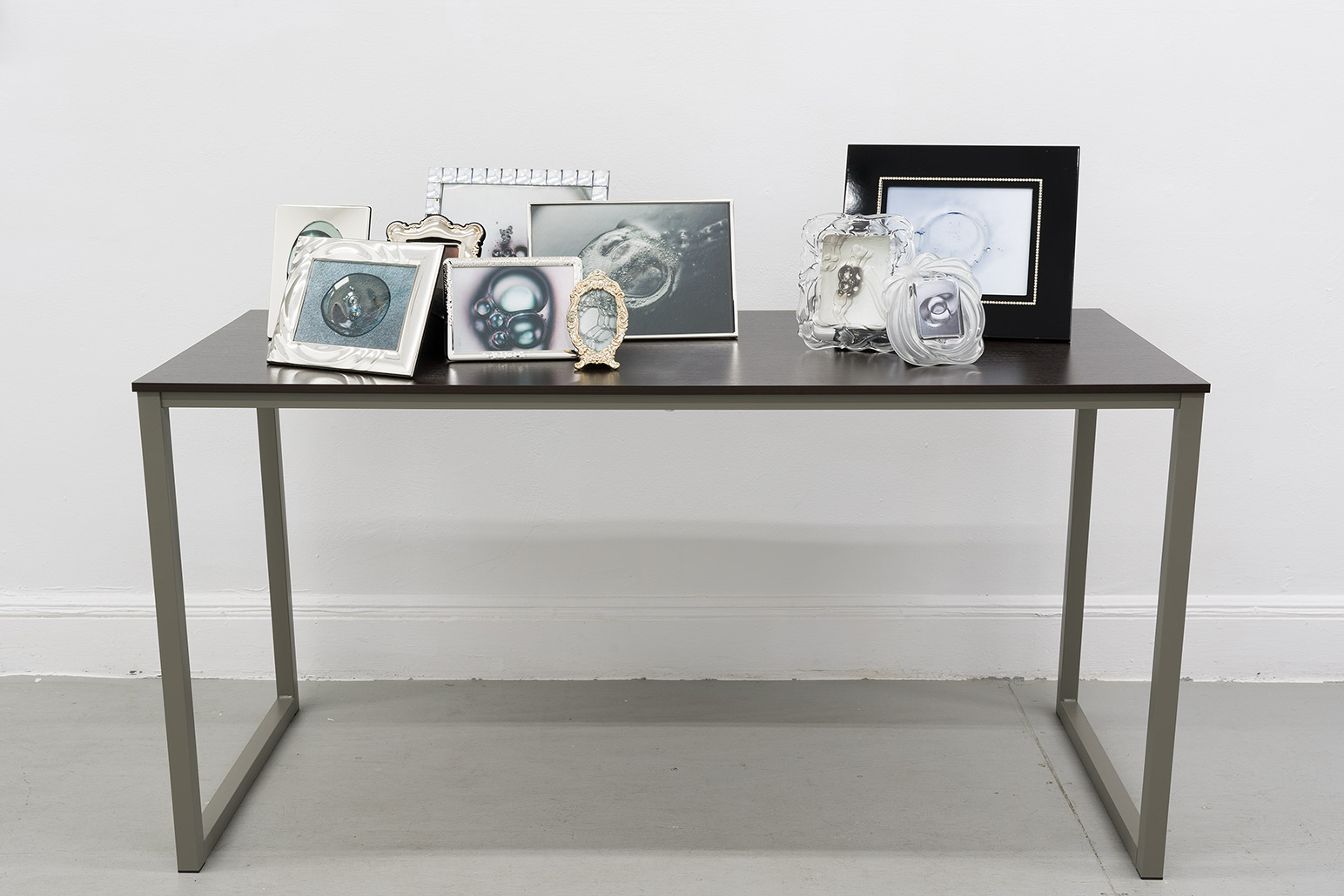 Gel, 2024, prints, frames, table, 39 x 55 x 24 in. (99.1 x 139.7 x 61 cm.)