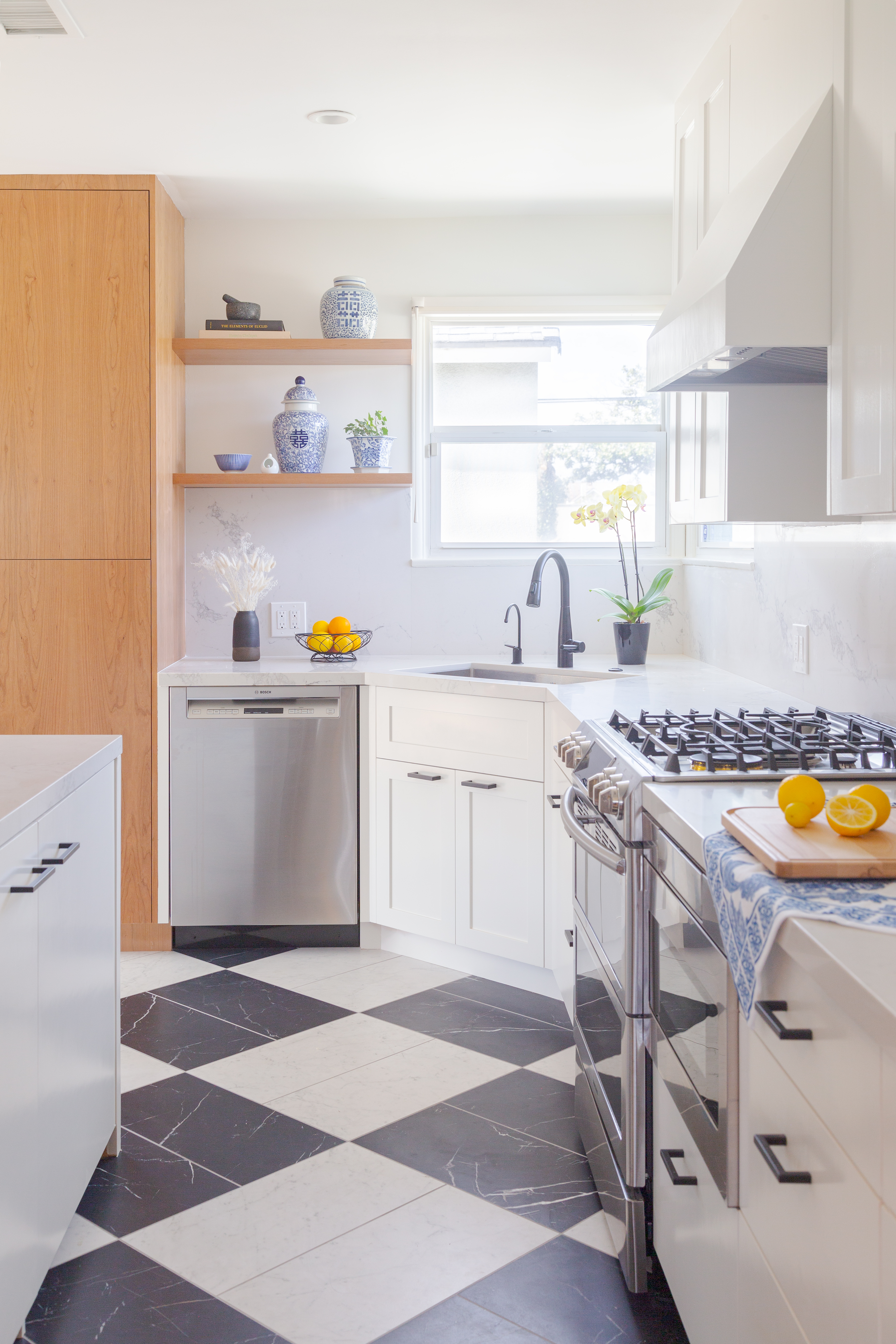 Our design honors the home's history with a modern take on the classic checkered floor by using large format marble look tiles to form its pattern, creating a heightened sense of scale and spaciousness in the narrow galley kitchen.