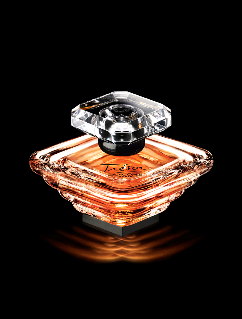 KMA photographer Isabelle Bonjean shoots a photograph of an orange perfume bottle with a black background for Lancome