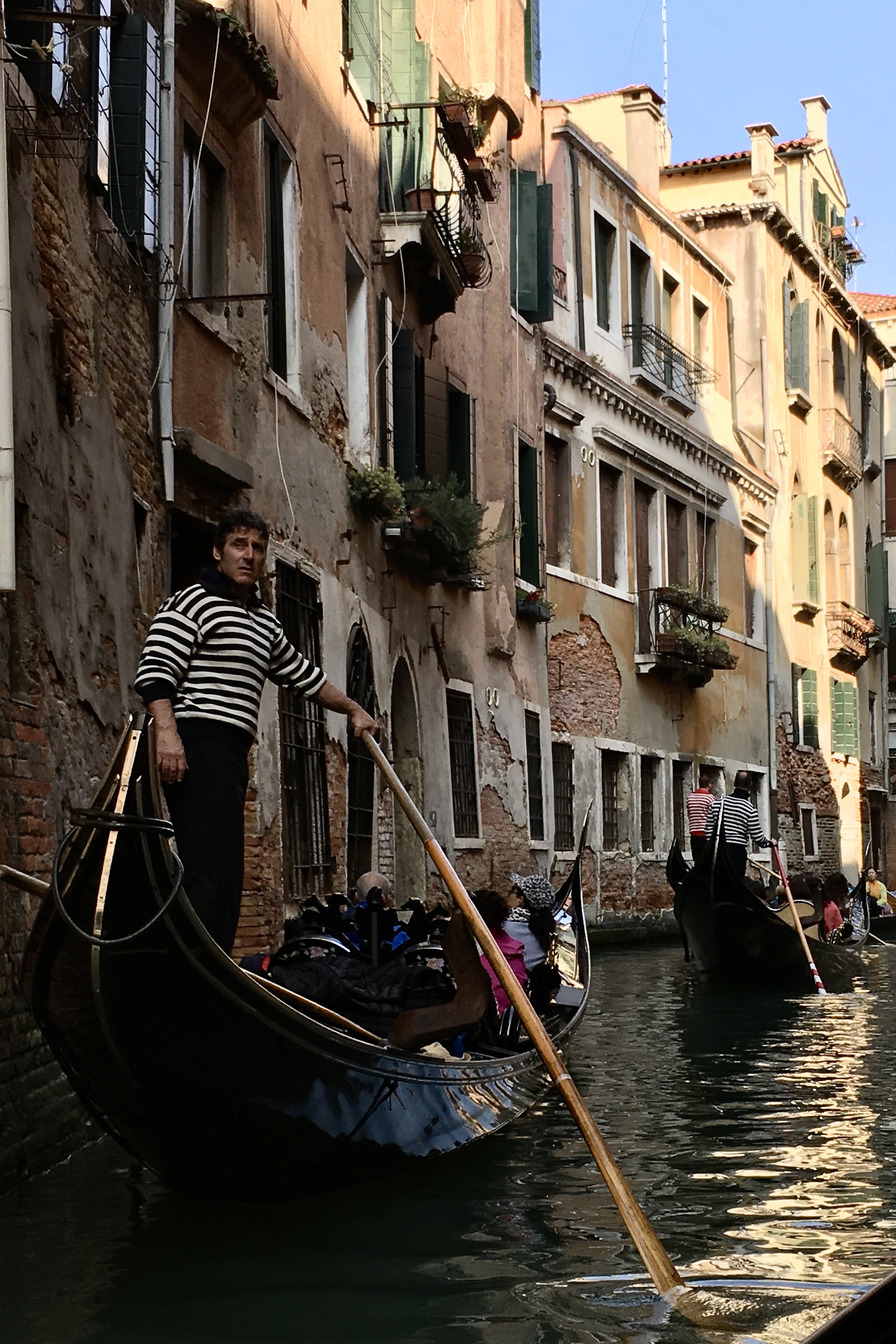 A classic Venetian gondola glides through the canals of Venice, Italy, reflecting historic architecture in the shimmering water.