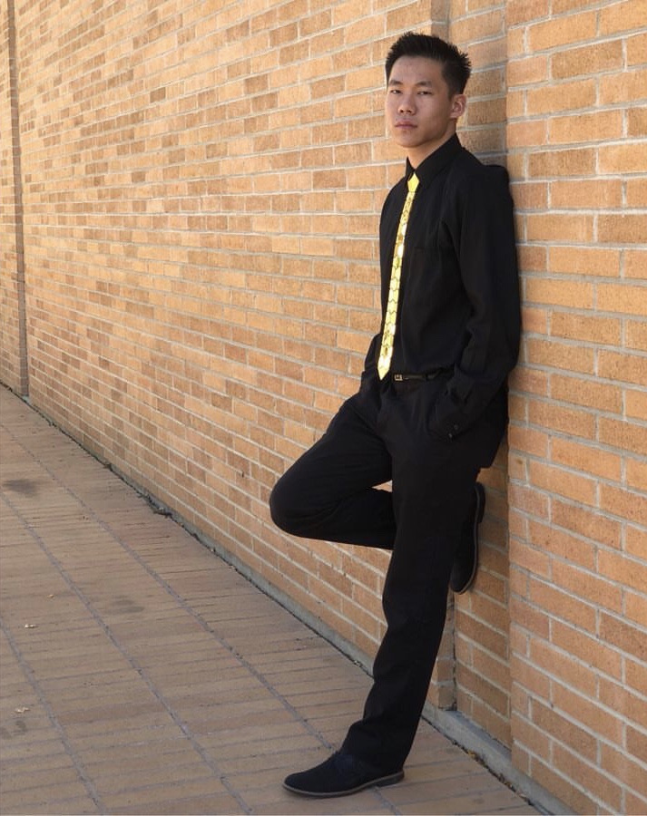 A person stands and leans against a brick wall.