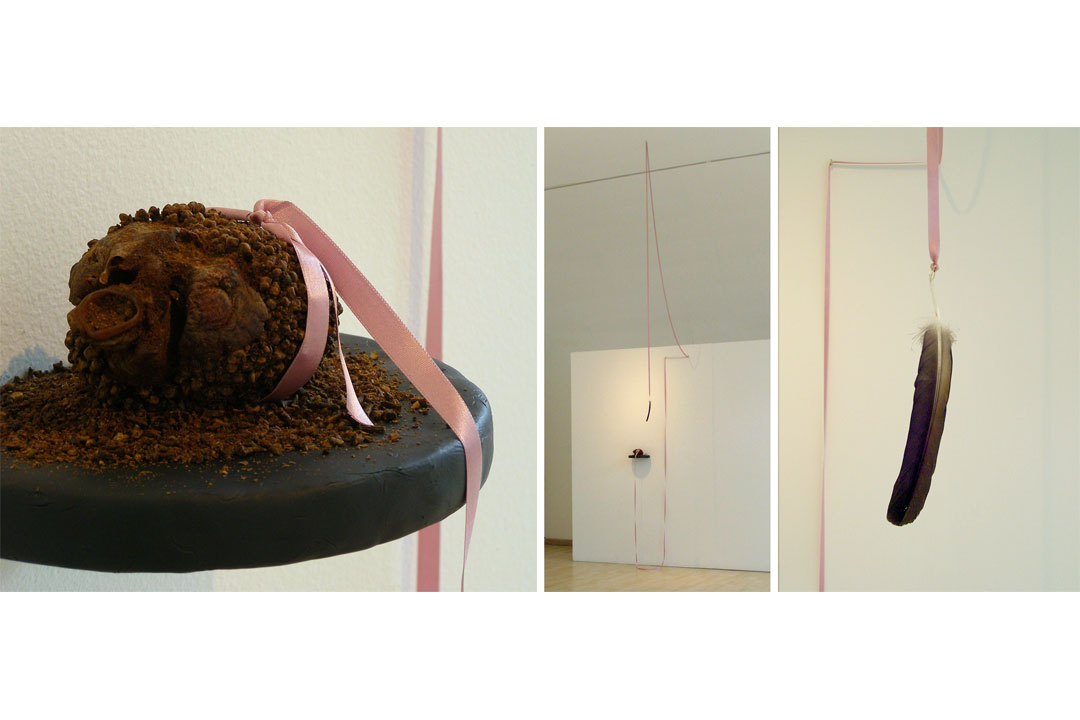 Maat. Corazón de cerdo conservado con clavos de olor, madera laminada, porcelanicrón, vinilo, cáncamos, cinta de satén, alambre de bronce y pluma de buitre. Dimensiones variables. 2011-2012