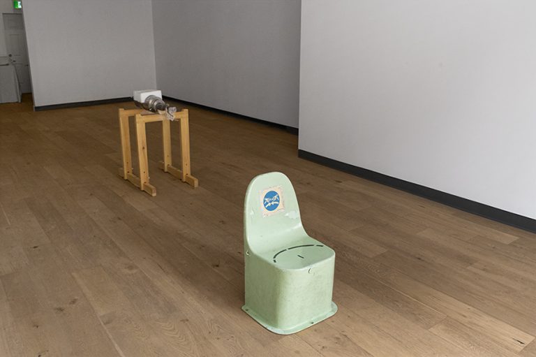 A photo capturing the engine piece and the green chair inside the gallery.