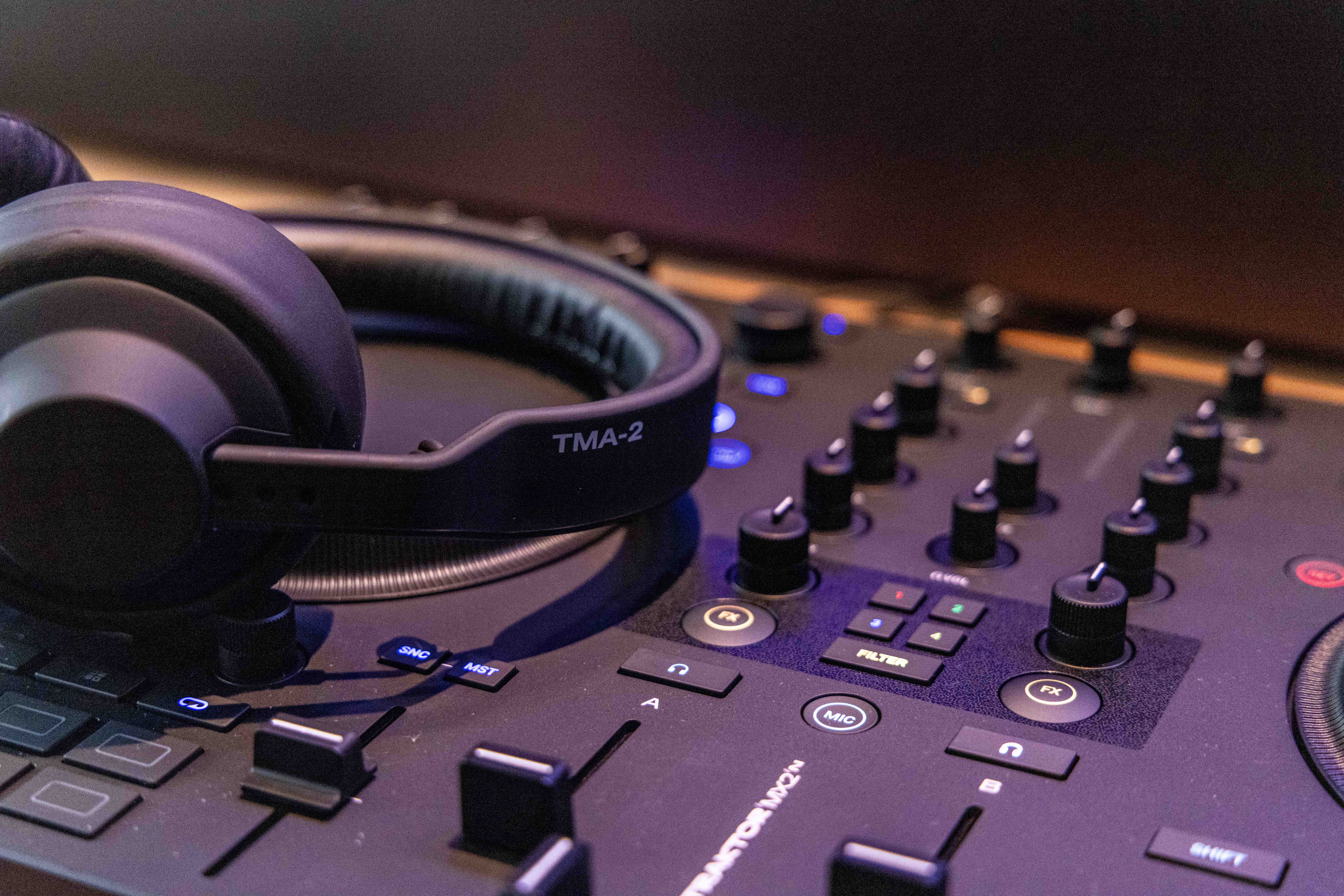 Close-up image of TMA-2 headphones resting on a Native Instruments controller at the ADE 2025 demo area.