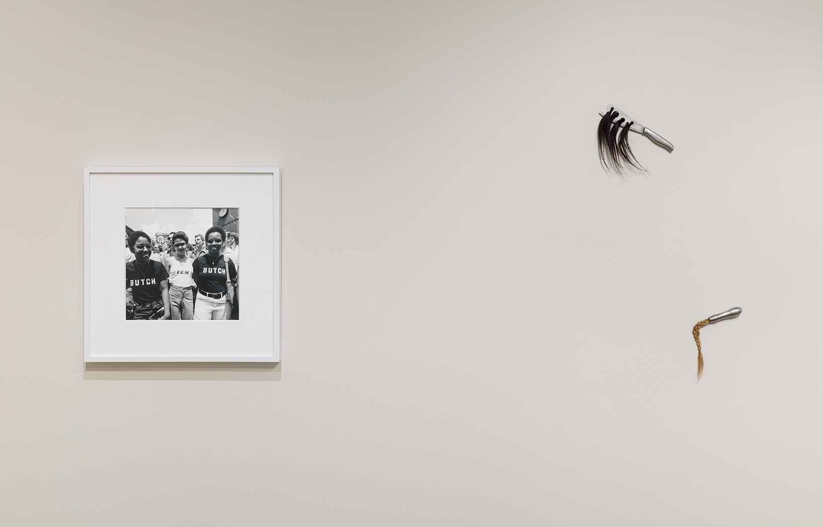 (left) Meryl Meisler, BUTCH FEM BUTCH, Christopher Street Liberation Day, NY, NY, June 26, 1977, 1977. Gelatin silver print, 16 x 20 inches. (right) Magdalena Dukiewicz, Object#15, 2023. Artist’s hair, found object, 10 x10 x 1.5 inches; Object #11, 2023. Artist’s hair, found object, 7 x 6 x 1.5 inches.Photo by Etienne Frossard.