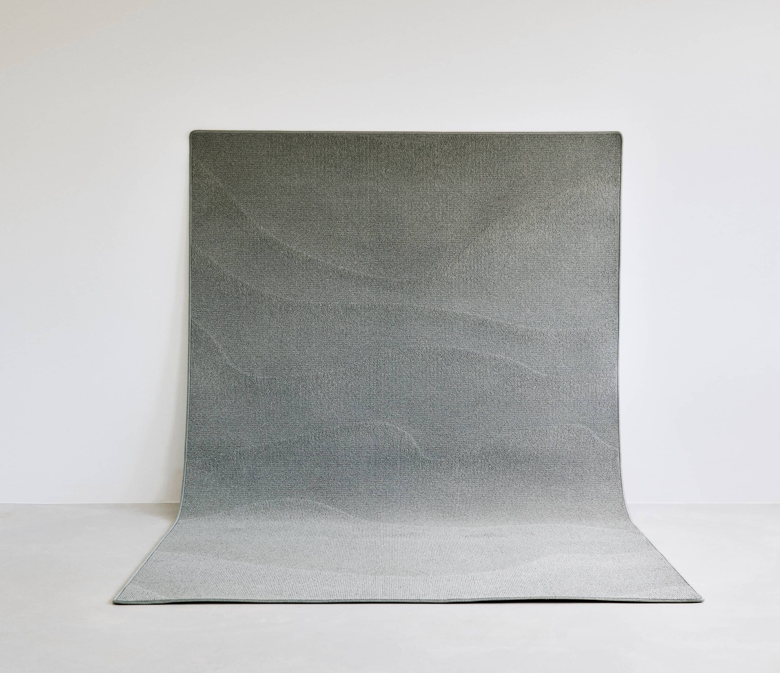 A NEW WAVE FOR EGEInspired by the rough and untouched landscape of the Danish west coast, A New Wave strives towards tactility on a functional and sensual level that allows you to feel the patterns of the sand, the strict lines of the grass dunes and the rhythm of the waves washing in. Multi levels in the carpet construction form the sculptural patterns while the colour palette reflects the dry and delicate tones of the seaside.The collection is crafted from regenerated and regenerable yarns based on abandoned fishing nets, used carpets and other industrial waste.Designed in collaboration with Laura BildeGo to product page →